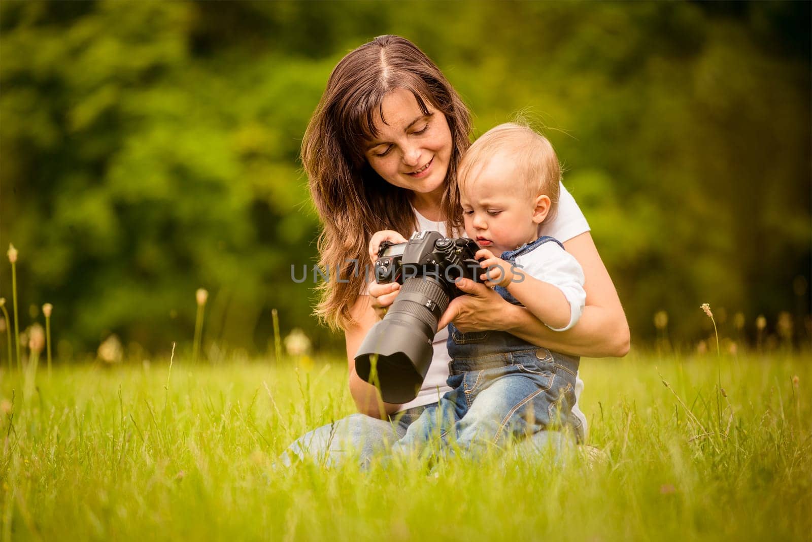 Mother showing her kid captured photos on dslr camera outdoor in nature