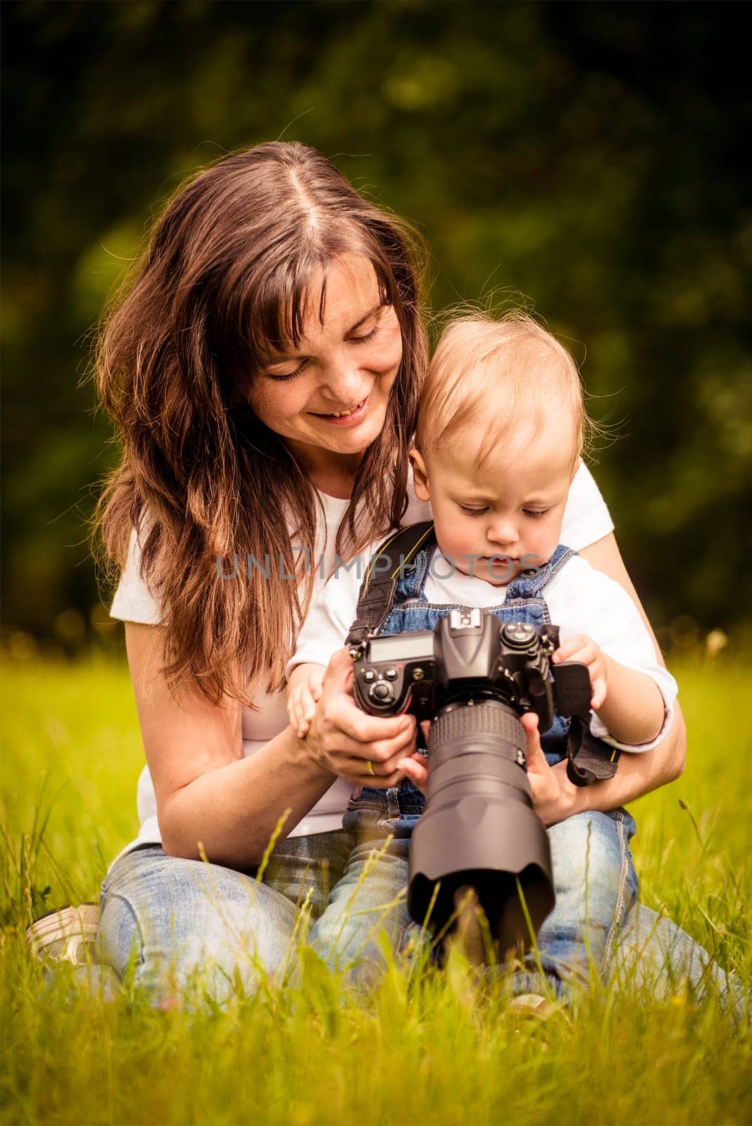 Mother showing her kid captured photos on dslr camera outdoor in nature