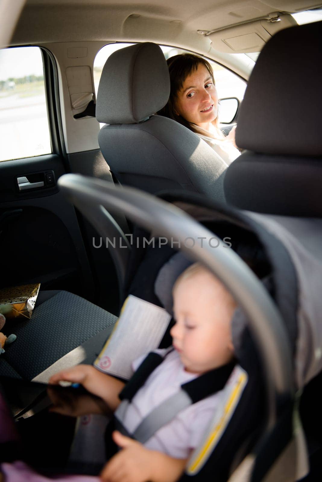 Mother and child inMother driving car and child sitting on back seat and playing with tablet car