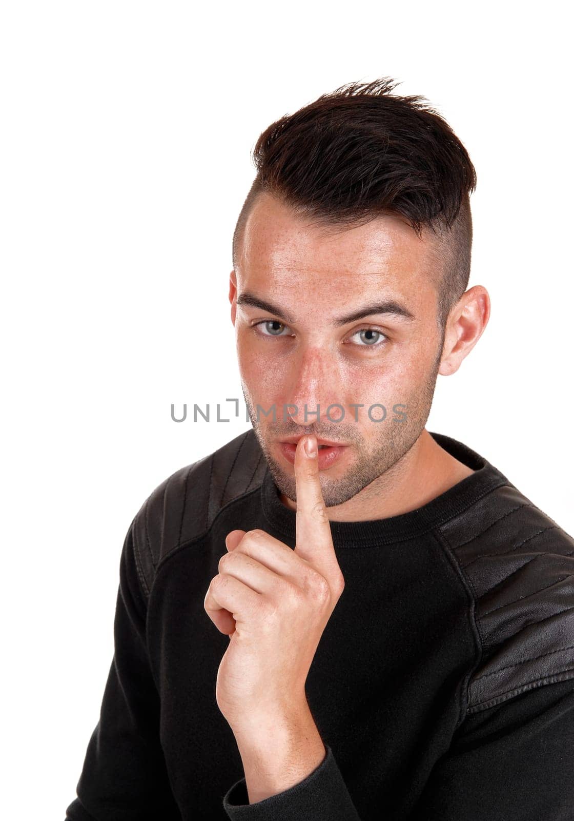 A young handsome man in a black sweater with his finger on his mouth, .isolated on white background..