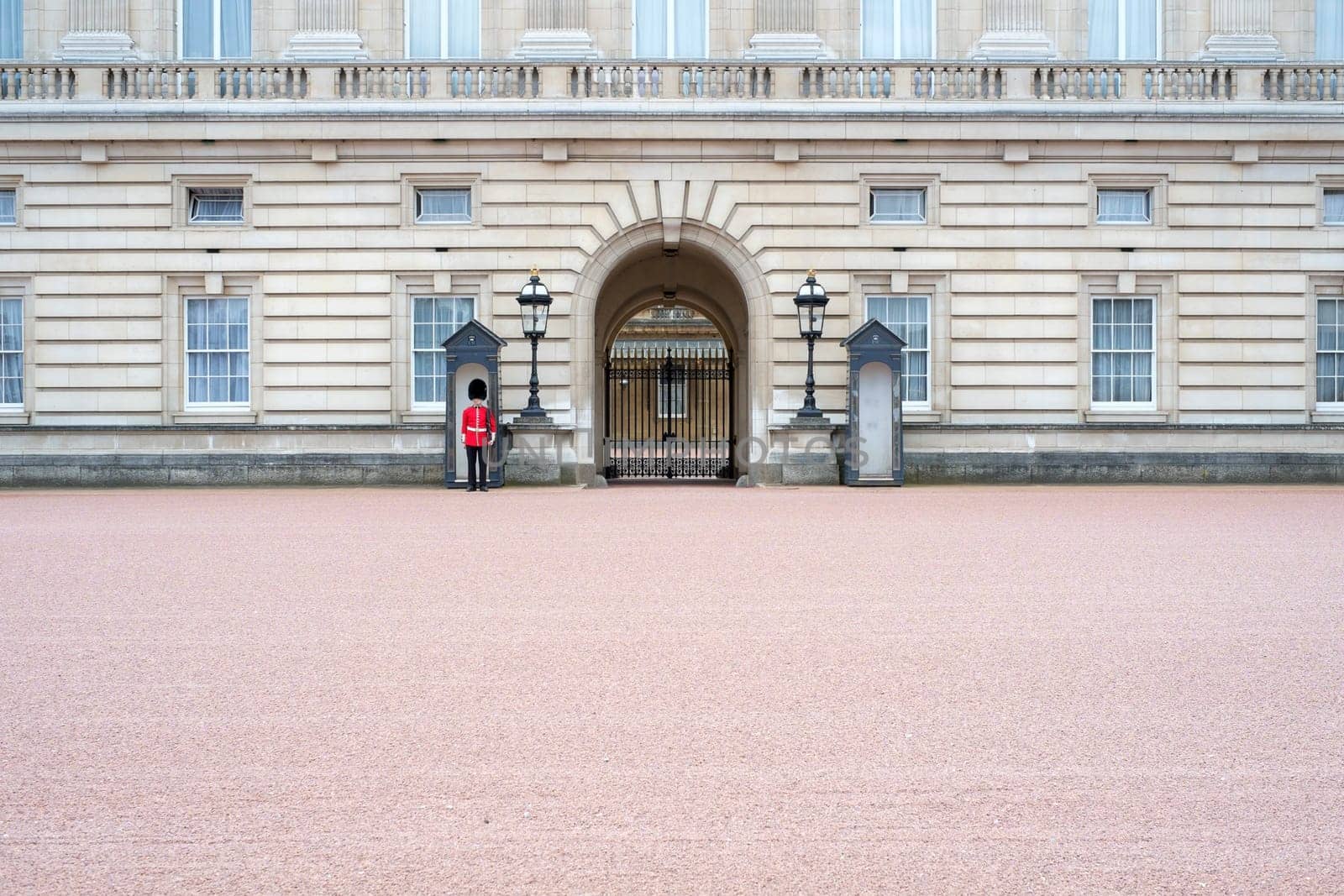 A lonely Queen's guard standing in front of Buckingham Palace gates in London, UK