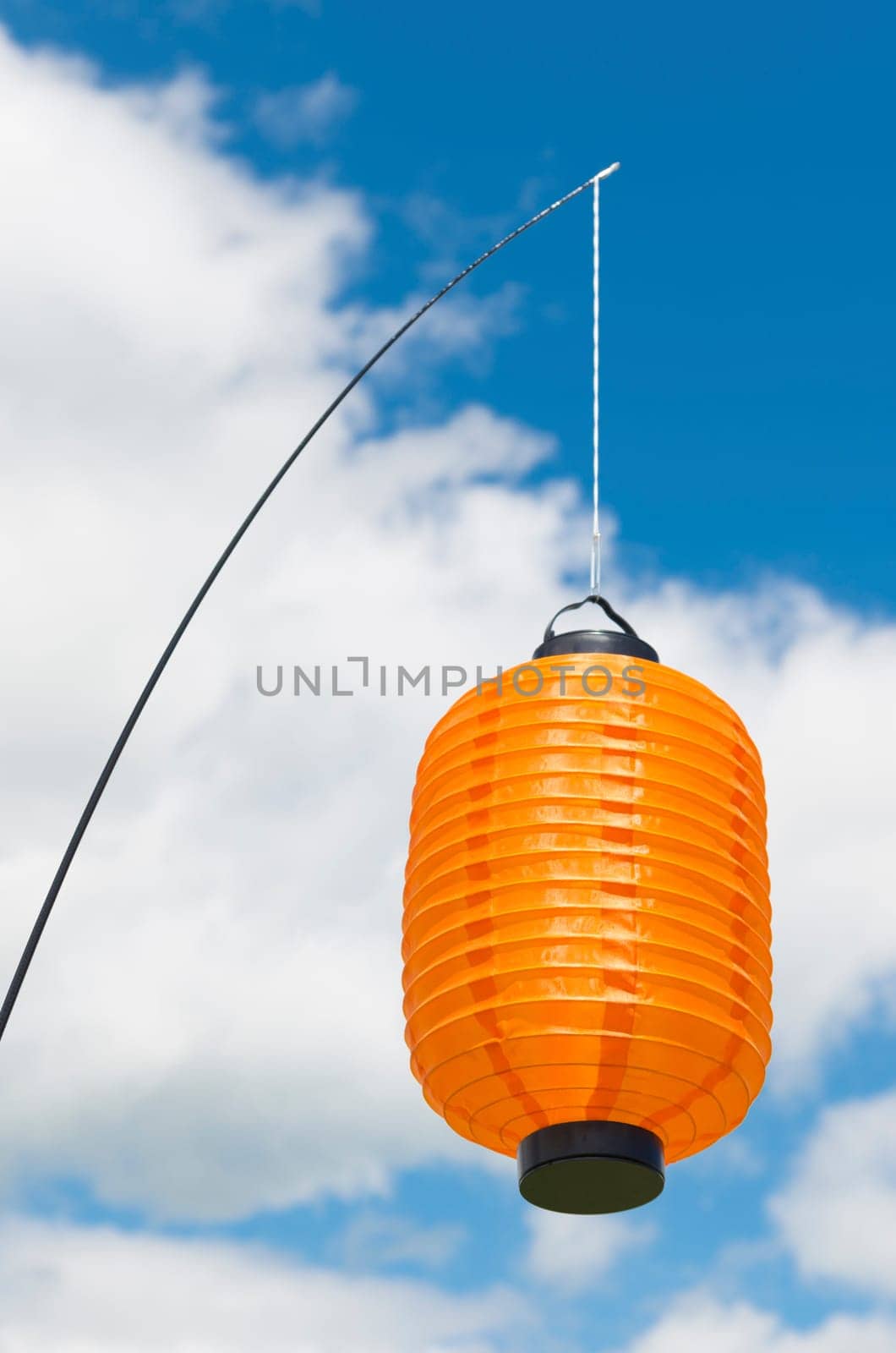 orange paper lantern hanging against a blue cloudy sky