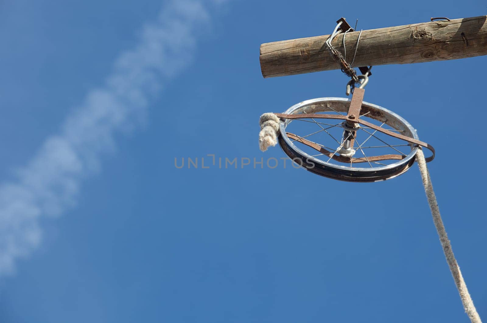 Wheel rim made of a baby trolley with rope over blue sky. It used for the renovation of the facade of the building