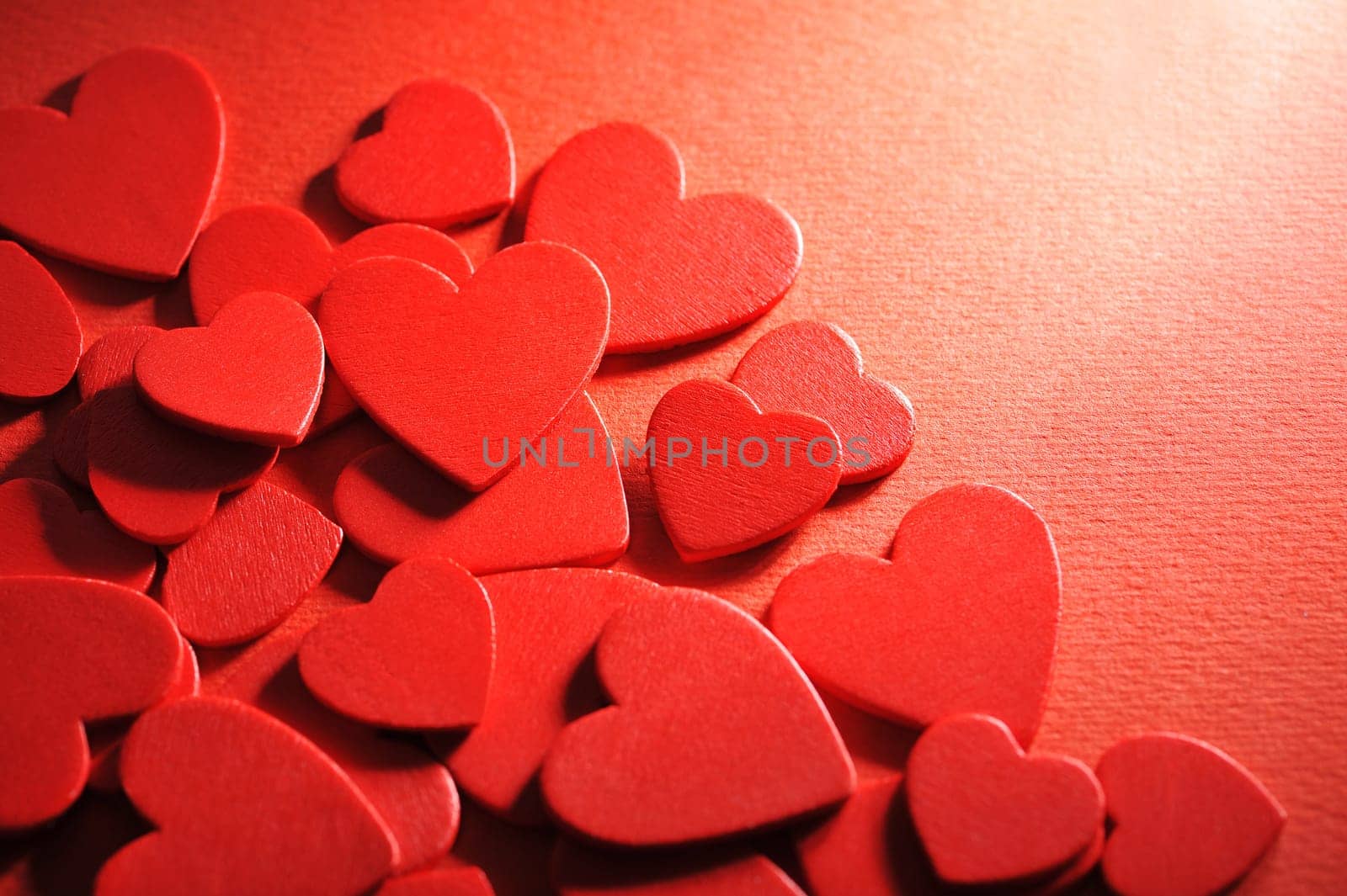 Many small red wooden hearts on a red background