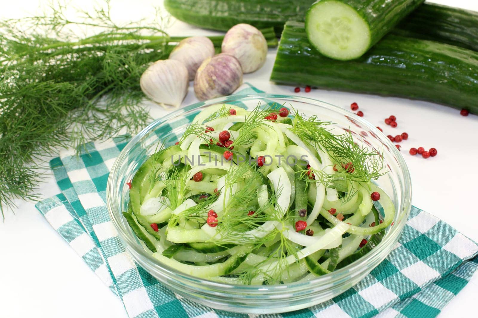 a bowl of cucumber salad with dill and red pepperberries