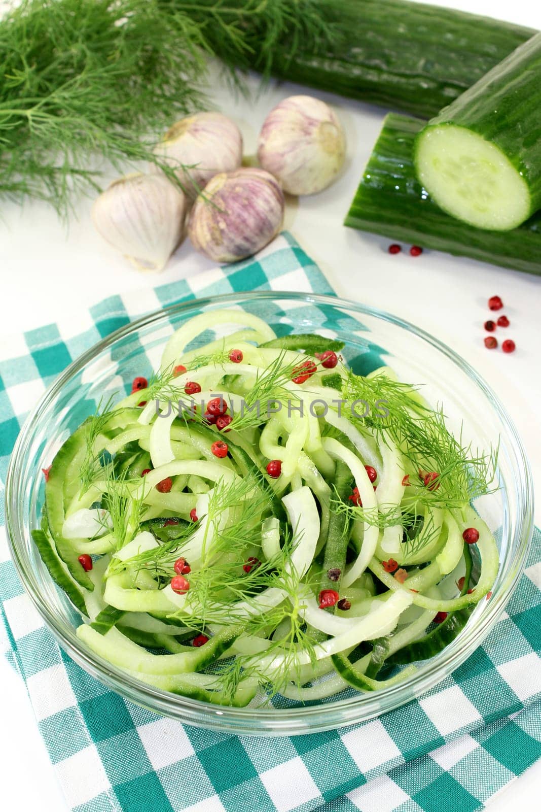 a bowl of cucumber salad with dill and red pepperberries