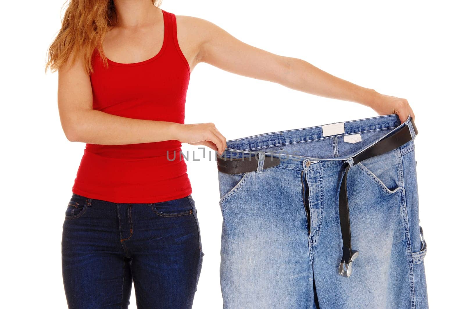 A young slim woman in jeans holding her old big jeans after she lost.much weight, isolated for white background..