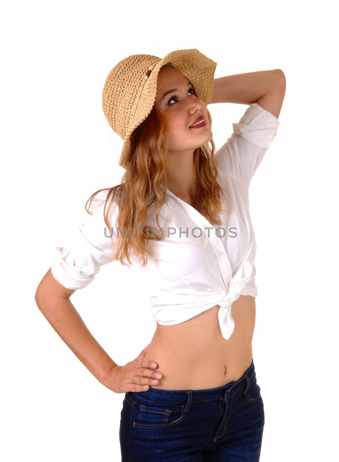 A beautiful young woman in a white blouse, jeans and a straw hat standing.isolated for white background, looking up..