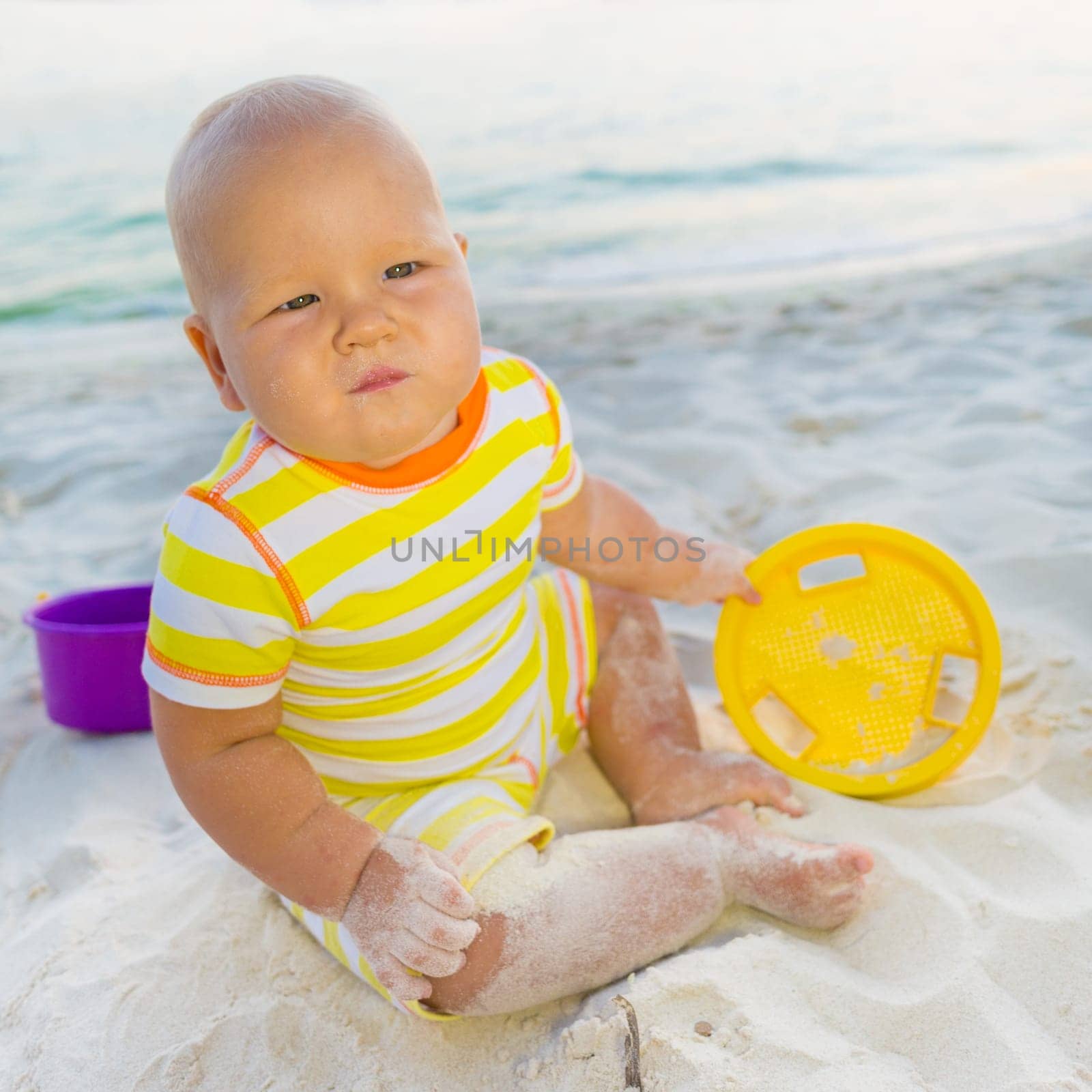 Cute baby on the tropical beach playing toys