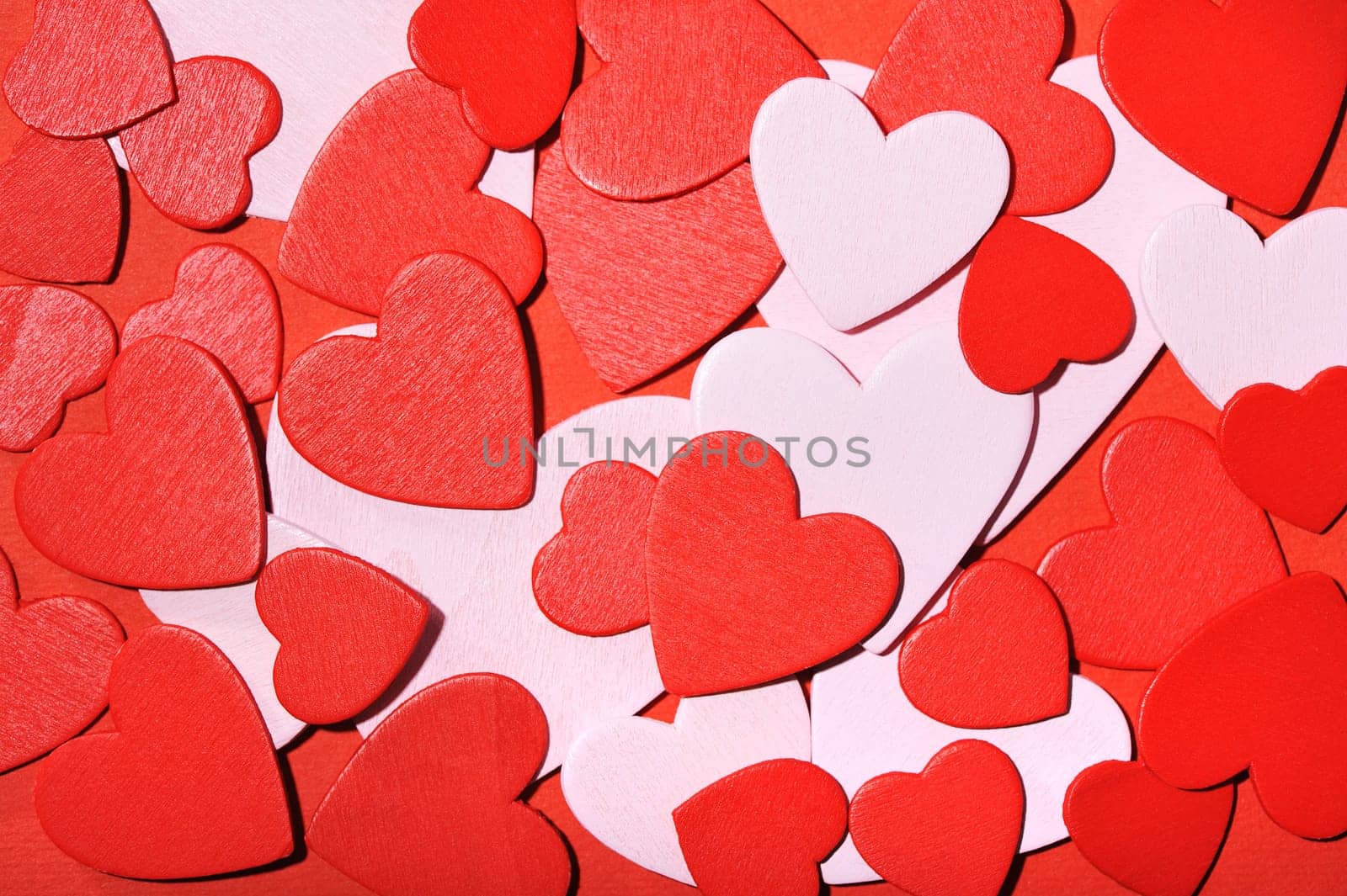 Many small red and white wooden hearts on a red background