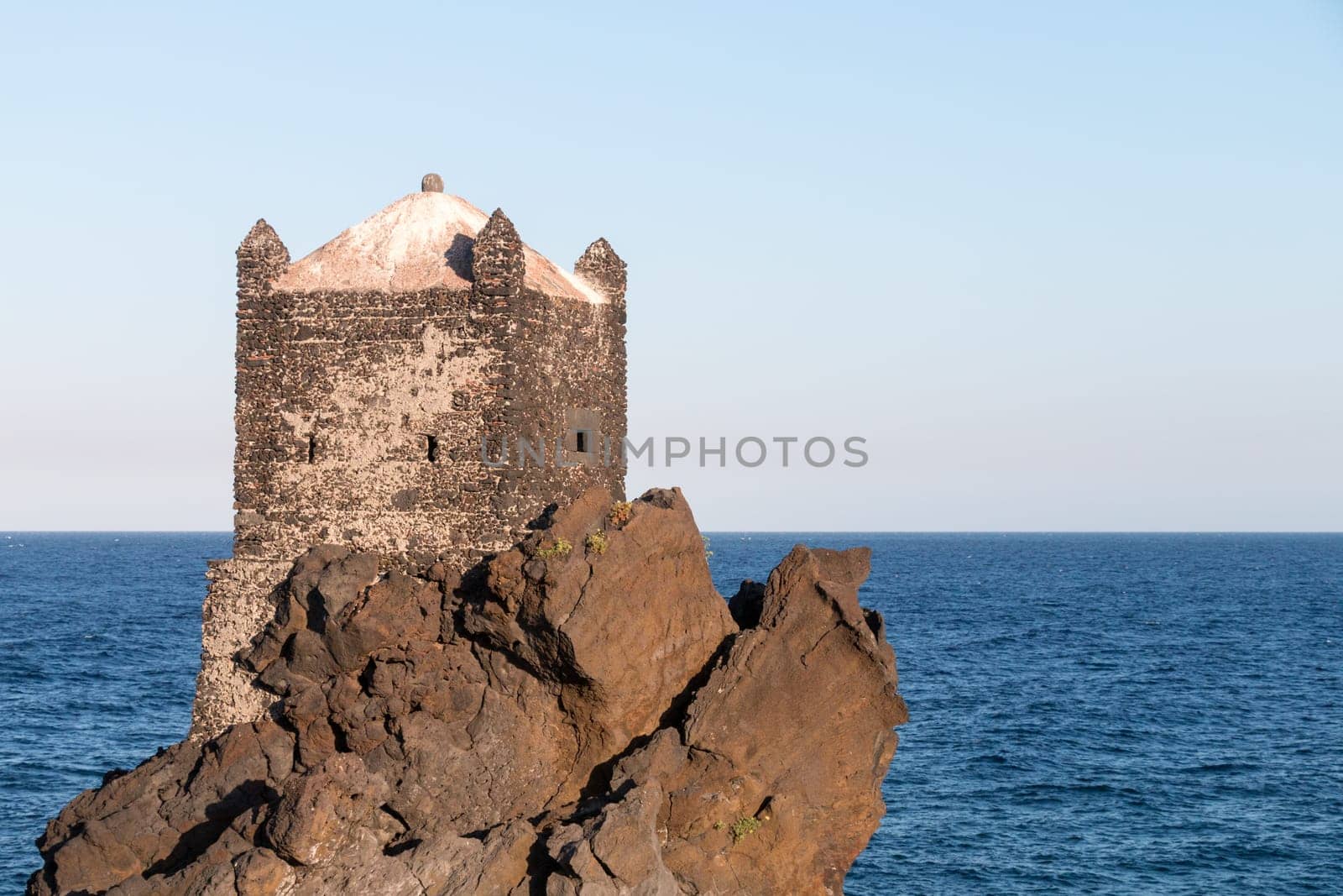 Medieval Tower build on lava stone in ionian sea Sicily