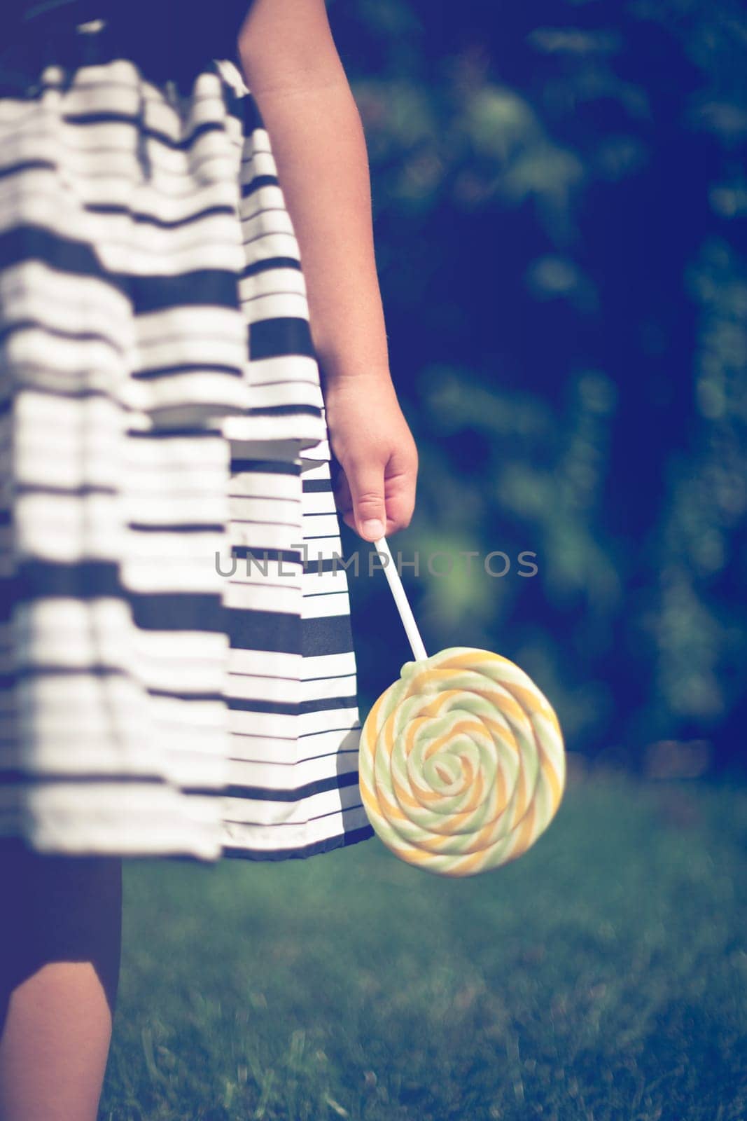 Little girl holding a lollipop in her hand. Closeup.