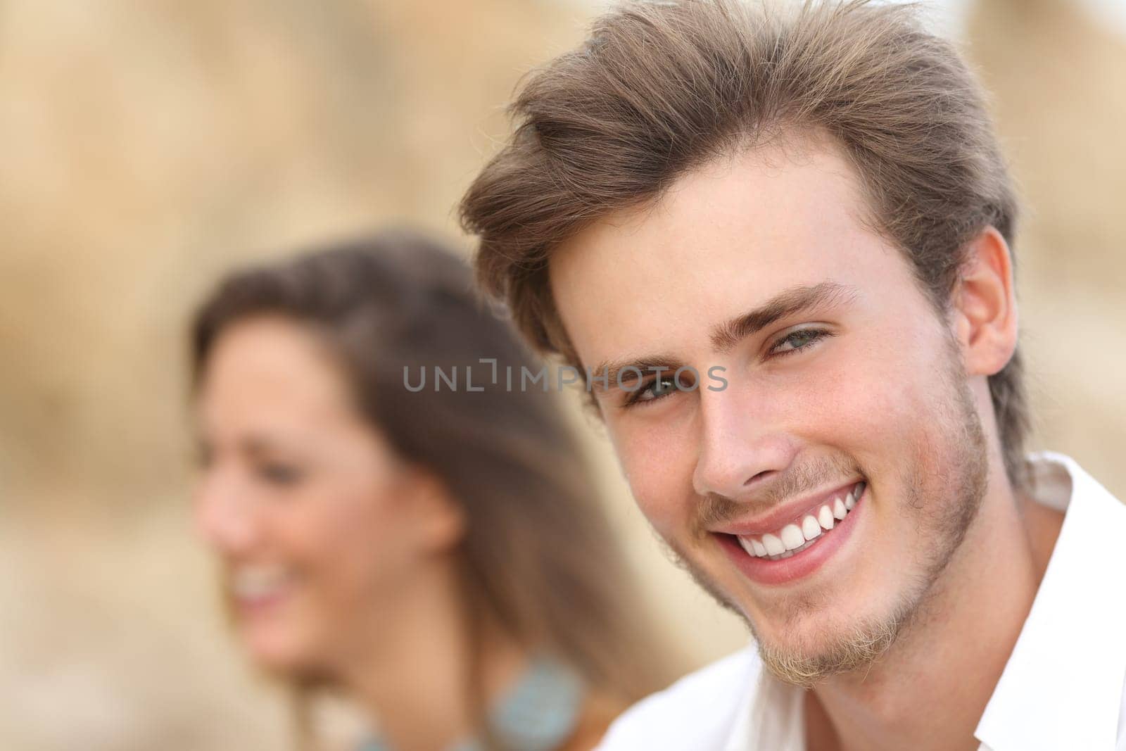 Handsome man close up portrait with a perfect white tooth and smile with a girl in the background