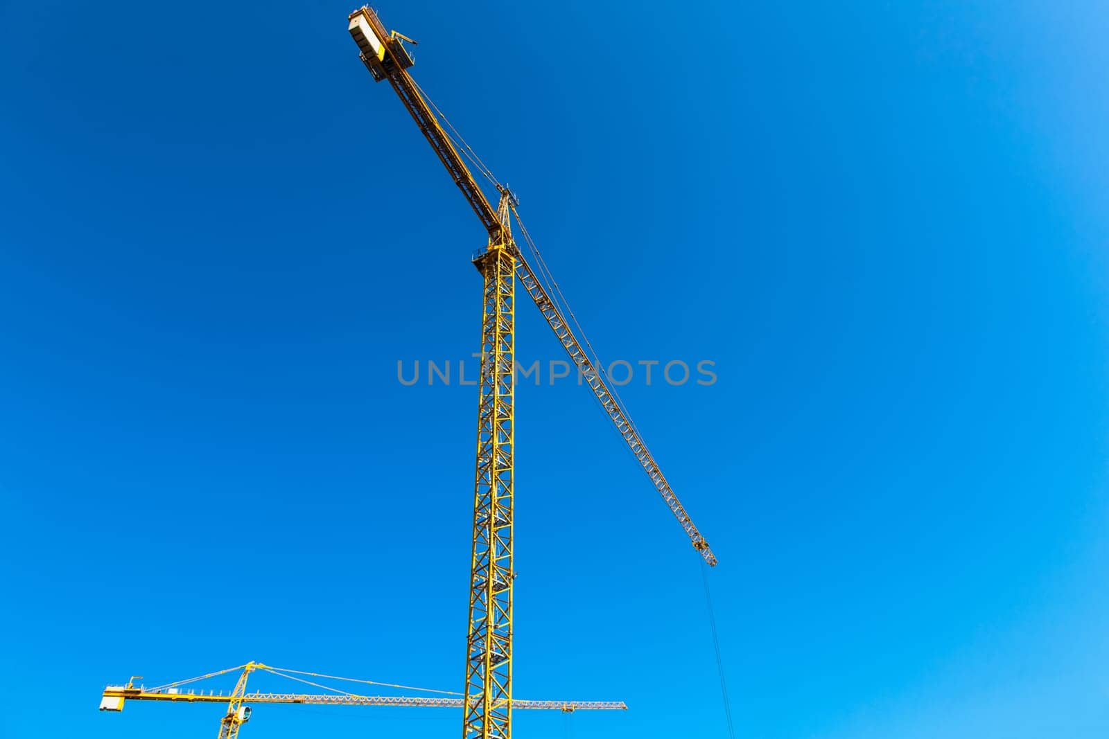 Construction cranes on blue sky background