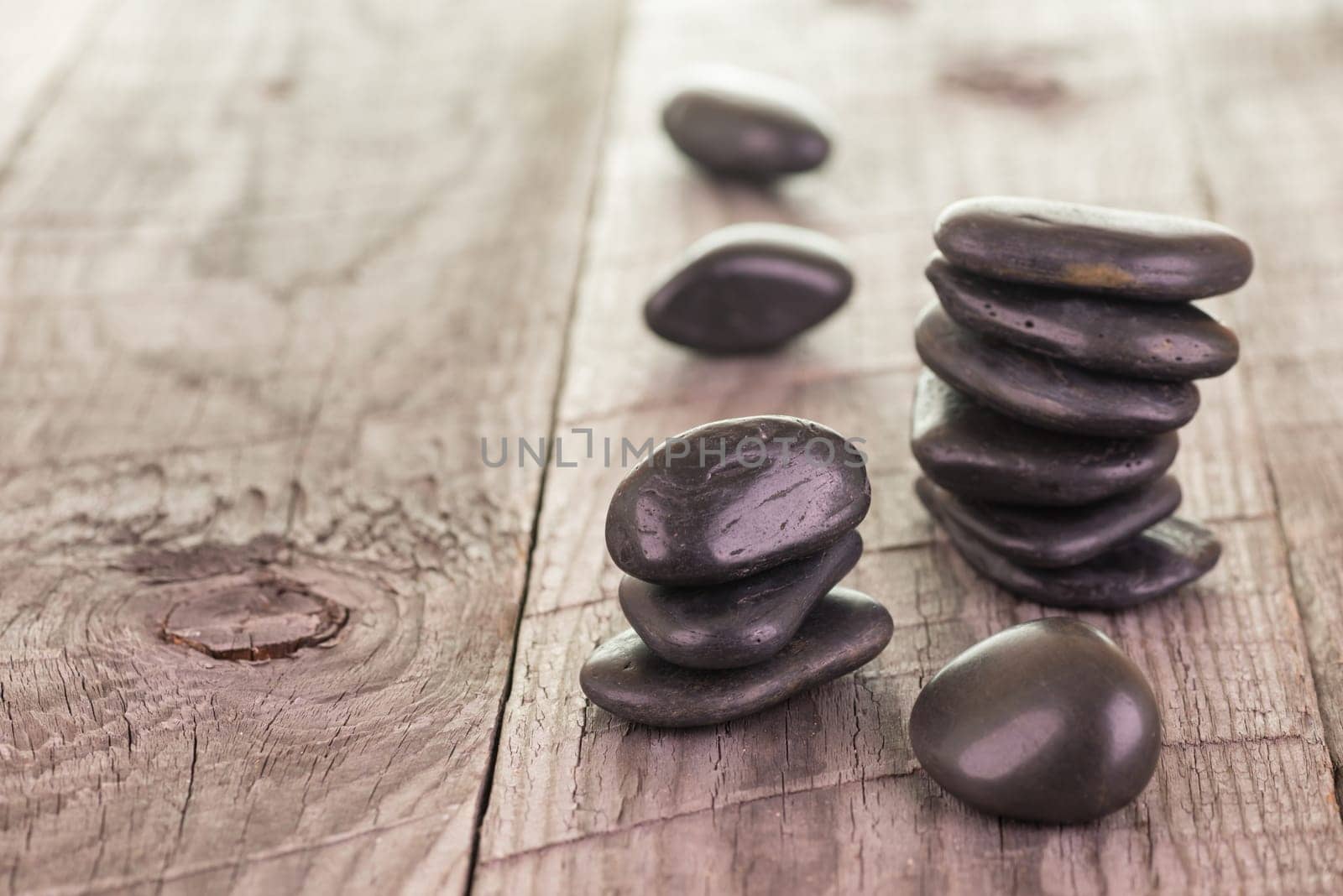Balanced black stones on weathered deck background