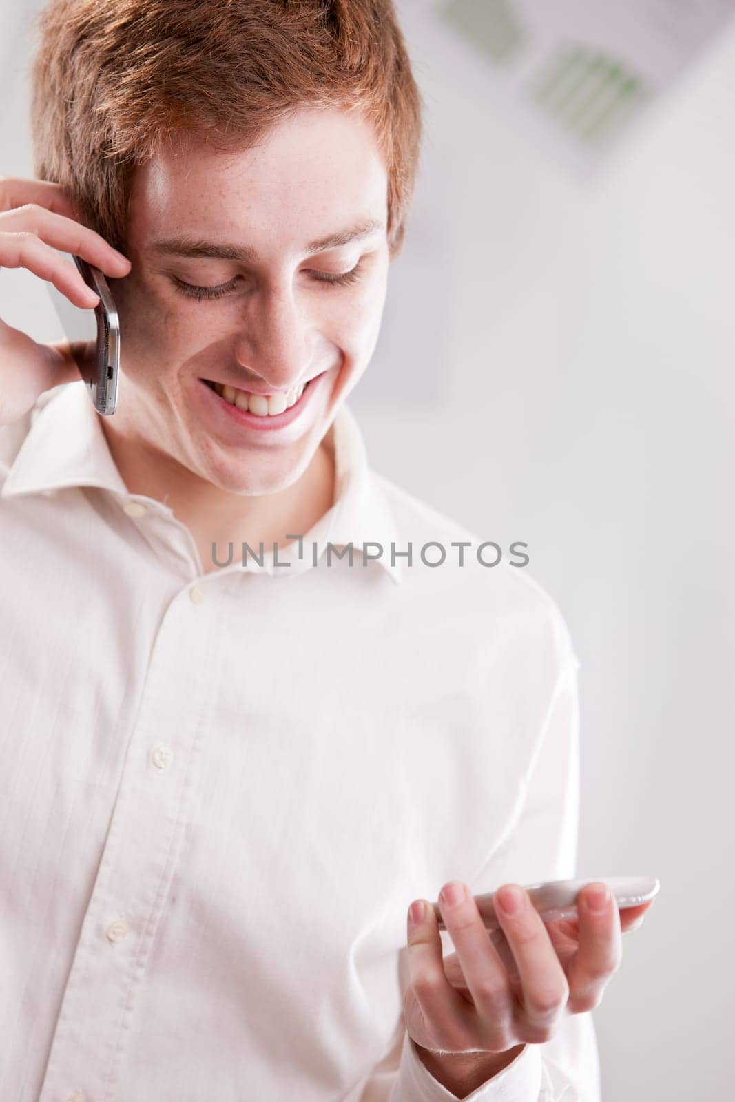 a happy geek fan of mobile phones calling with two cellular phones