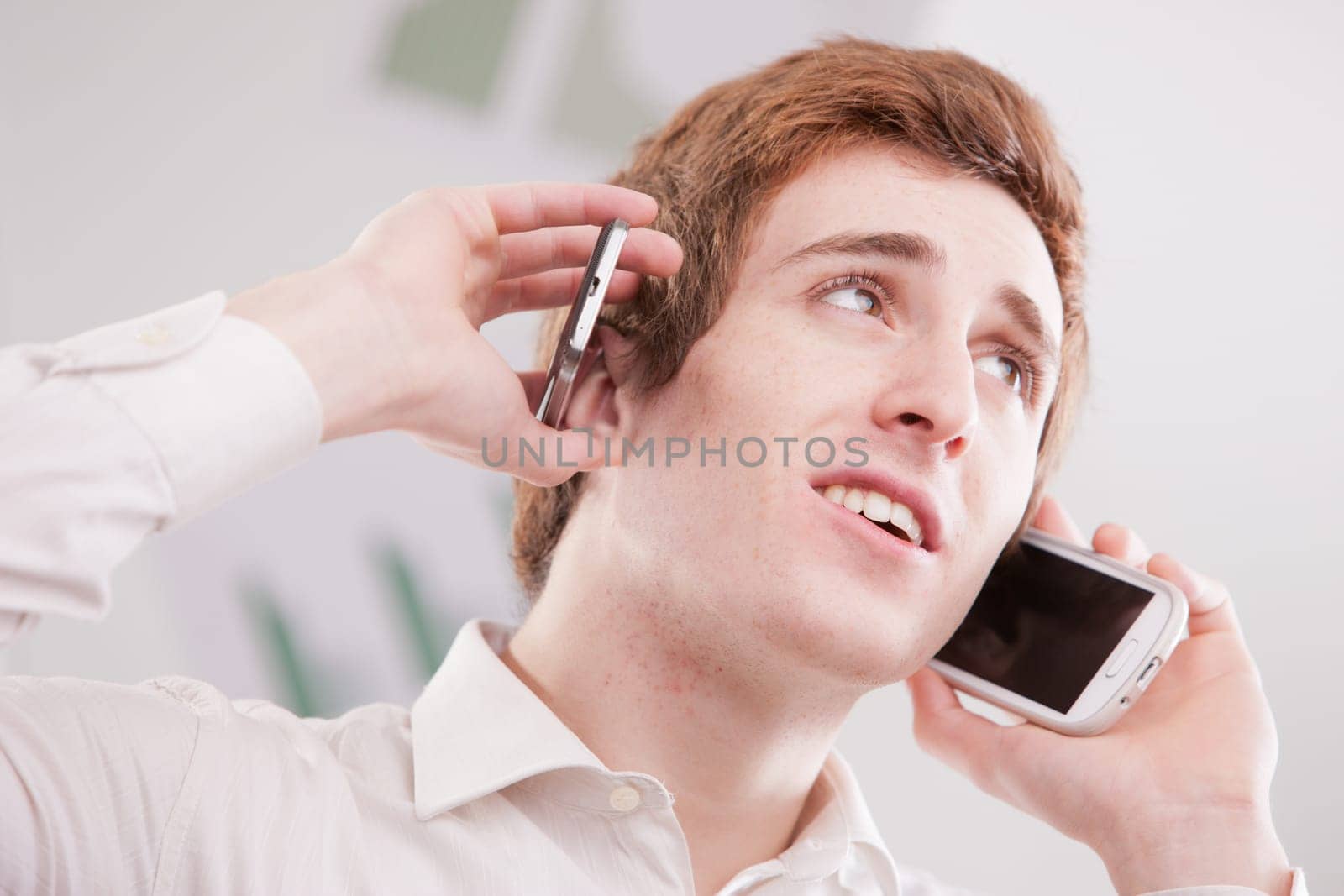 a happy geek fan of mobile phones calling with two cellular phones