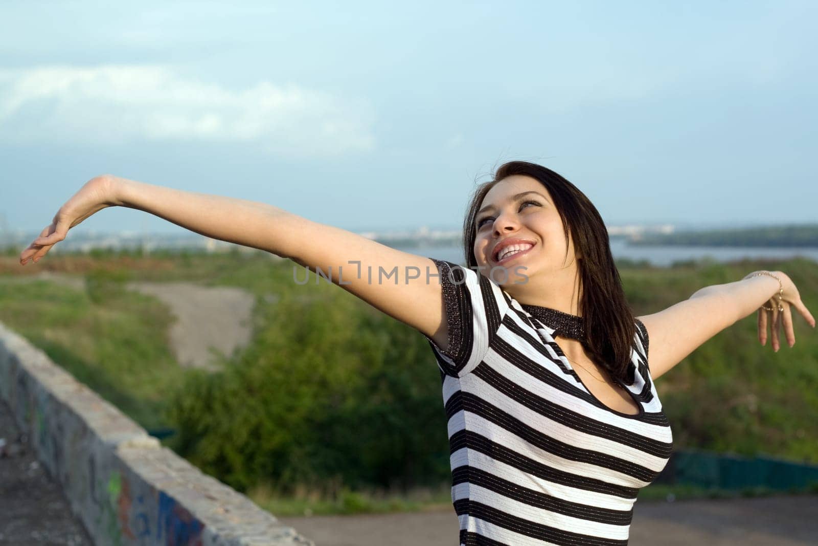 Happy young woman with arms raised outdoors