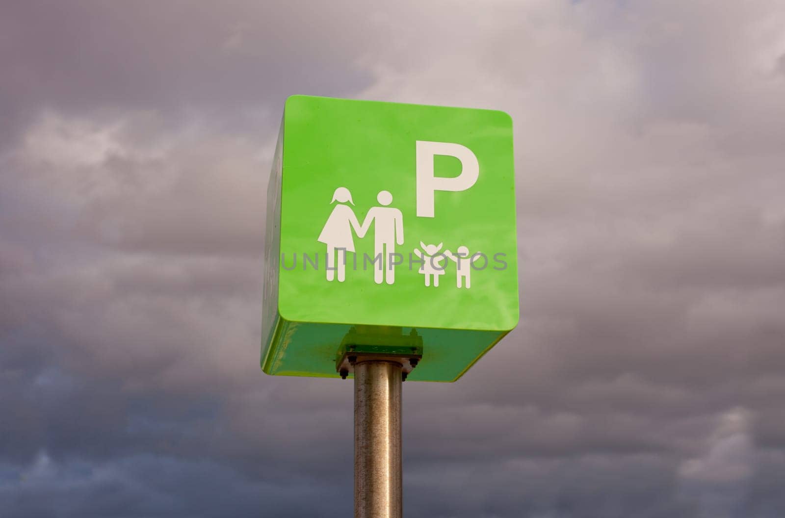 Reserved car park pole green sign for family against cloudy sky sky