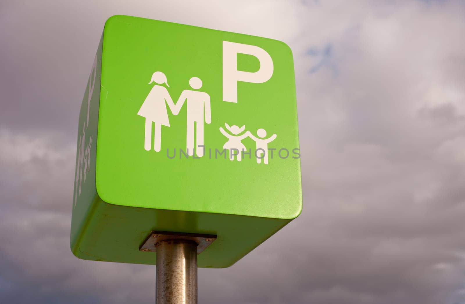 Reserved car park pole green sign for family against cloudy sky sky
