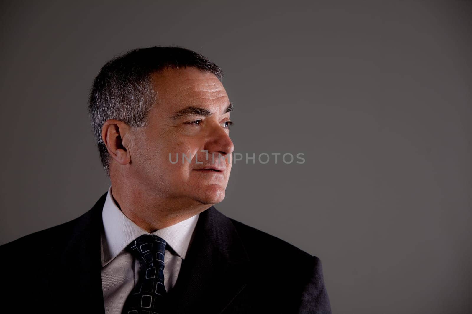 Senior with suit and tie very self confident looking at his side