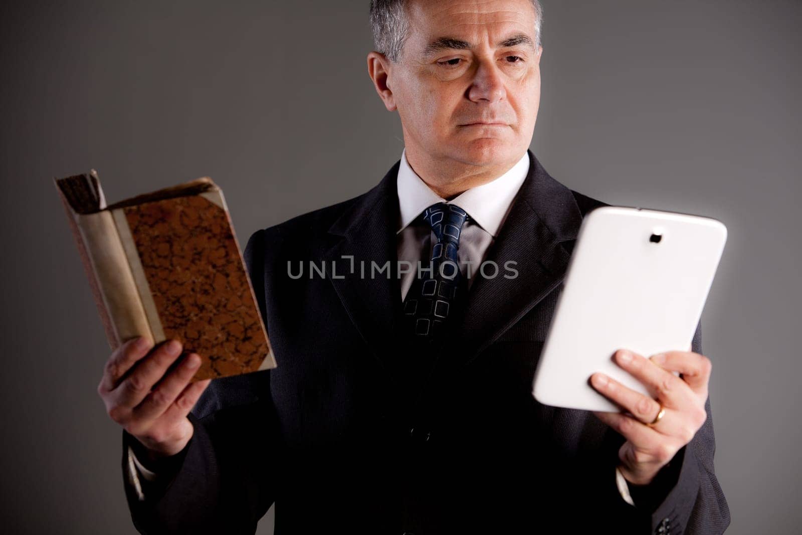 An old expert comparing a book and a tablet maybe an e-book to check which one is the best