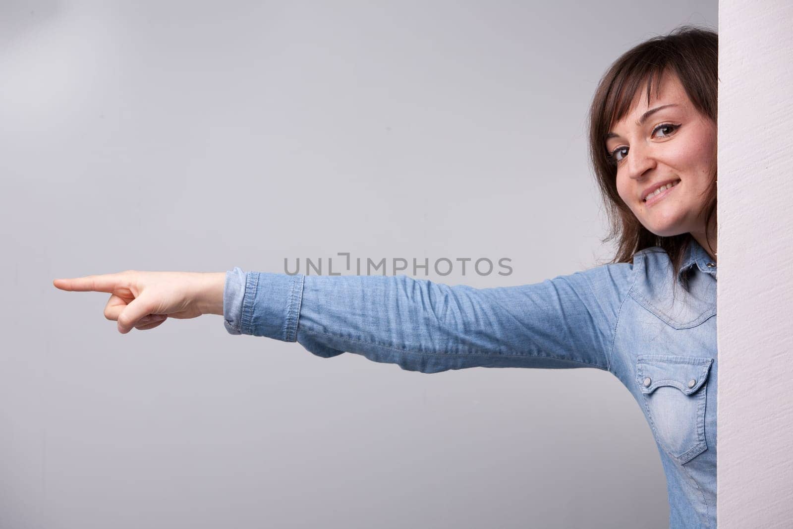 girl pointing out with her entire arm behind the wall