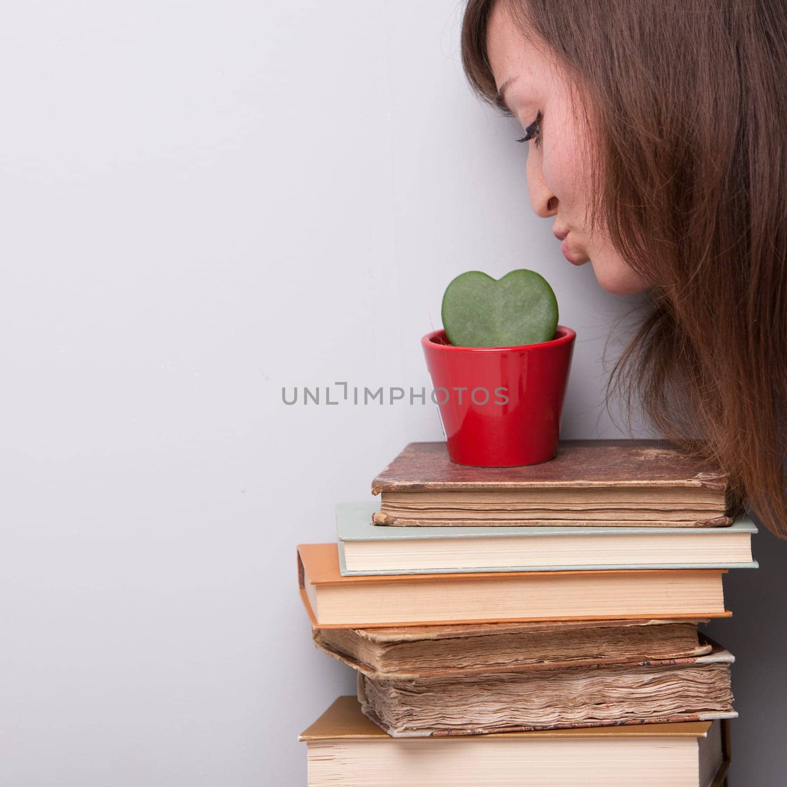 lovely girl loving her plant and her books sitting on the floor of her house in relax