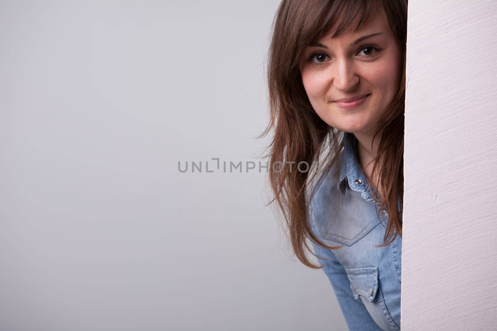 Nice girl showing up behind the white wall