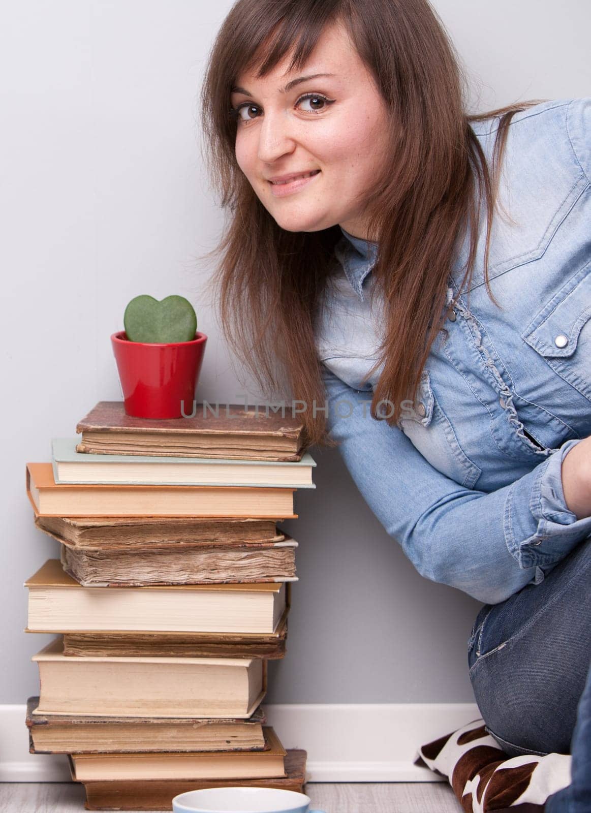 lovely girl loving her plant and her books sitting on the floor of her house in relax