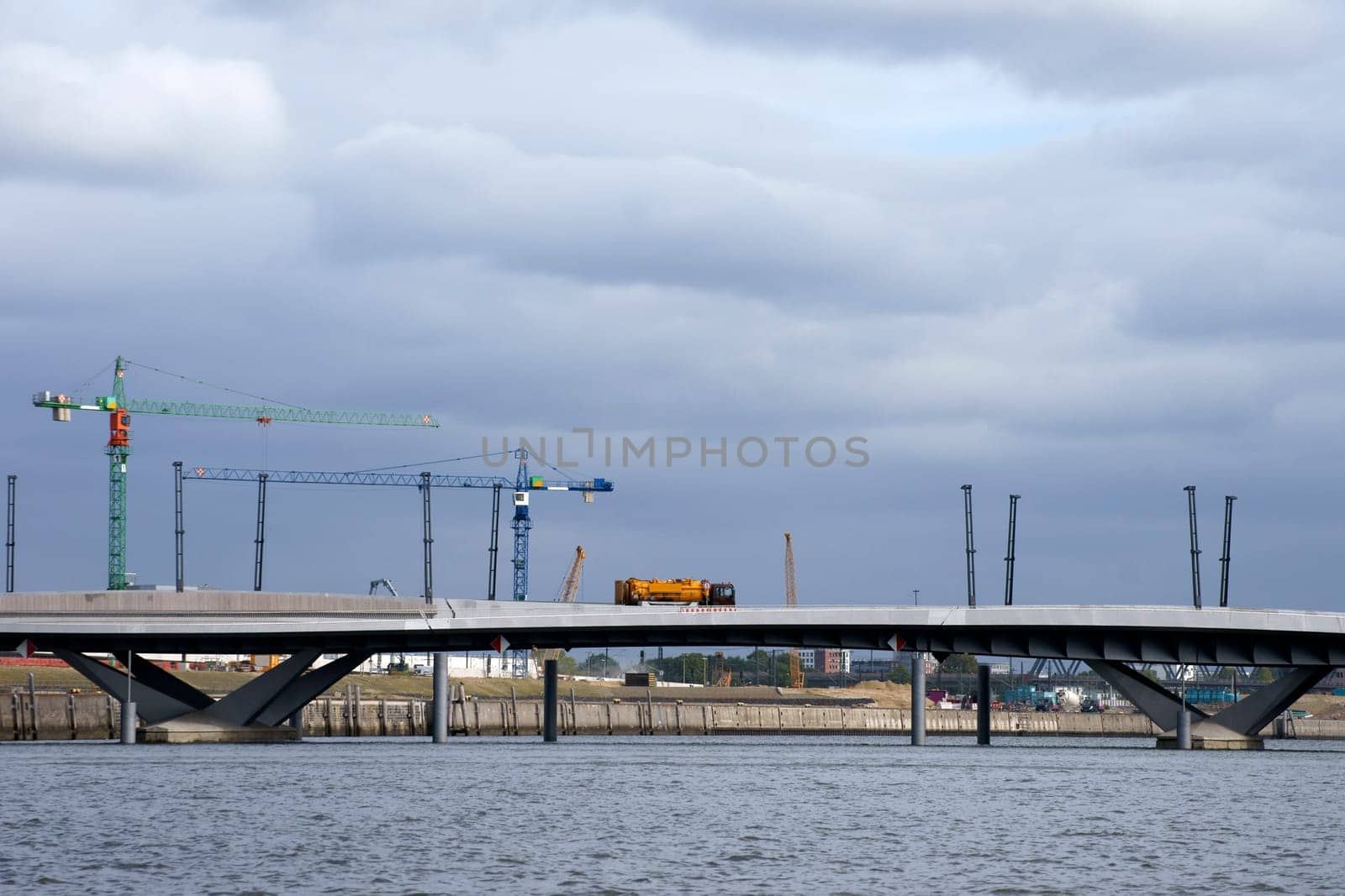 A lorry crosses a newly built bridge with construction sites and cranes.
