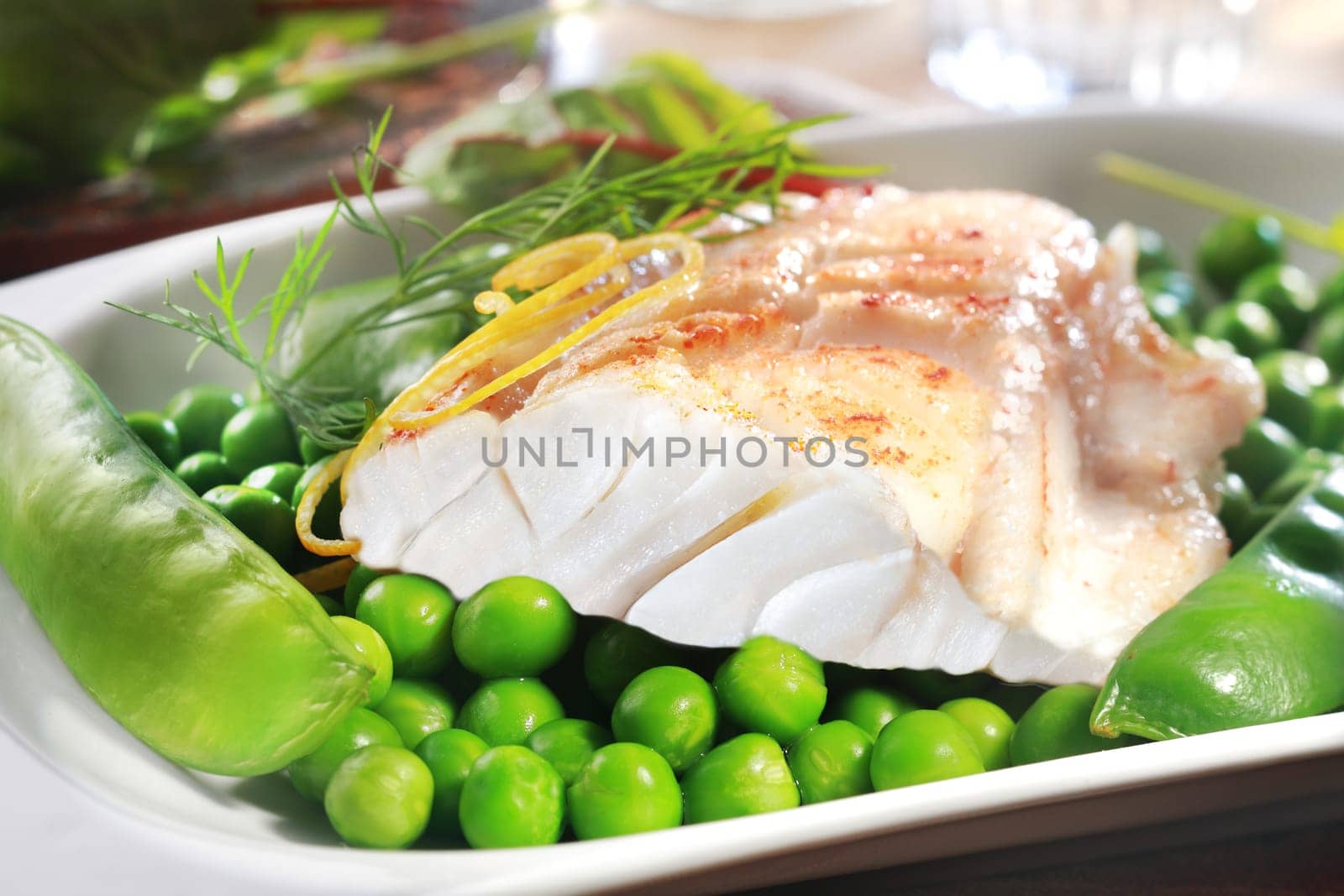 Healthy grilled fish steak with peas, mangetouts and lemon zest served on a plate as an appetizer or main course