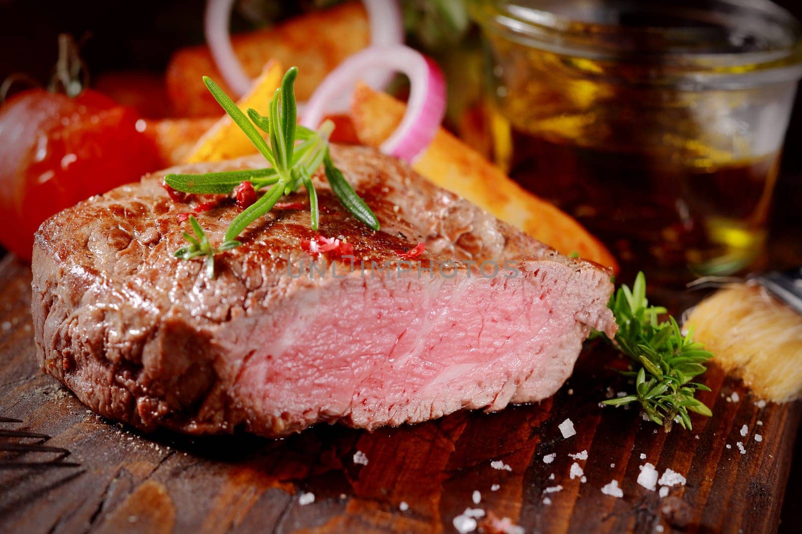 Succulent tender rare beef steak grilled to perfection sliced through to show the texture seasoned with fresh rosemary and salt