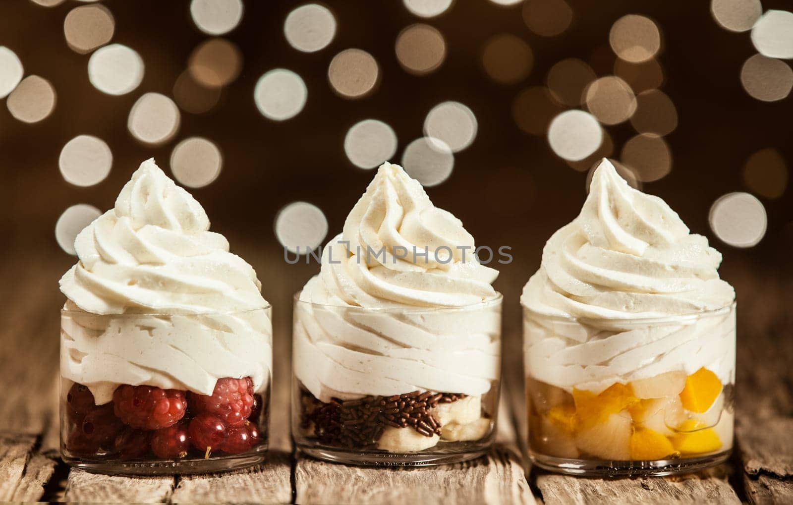 Yummy Frozen Yogurt on Round Glass Containers with Assorted Fruits Placed on Wooden Table.