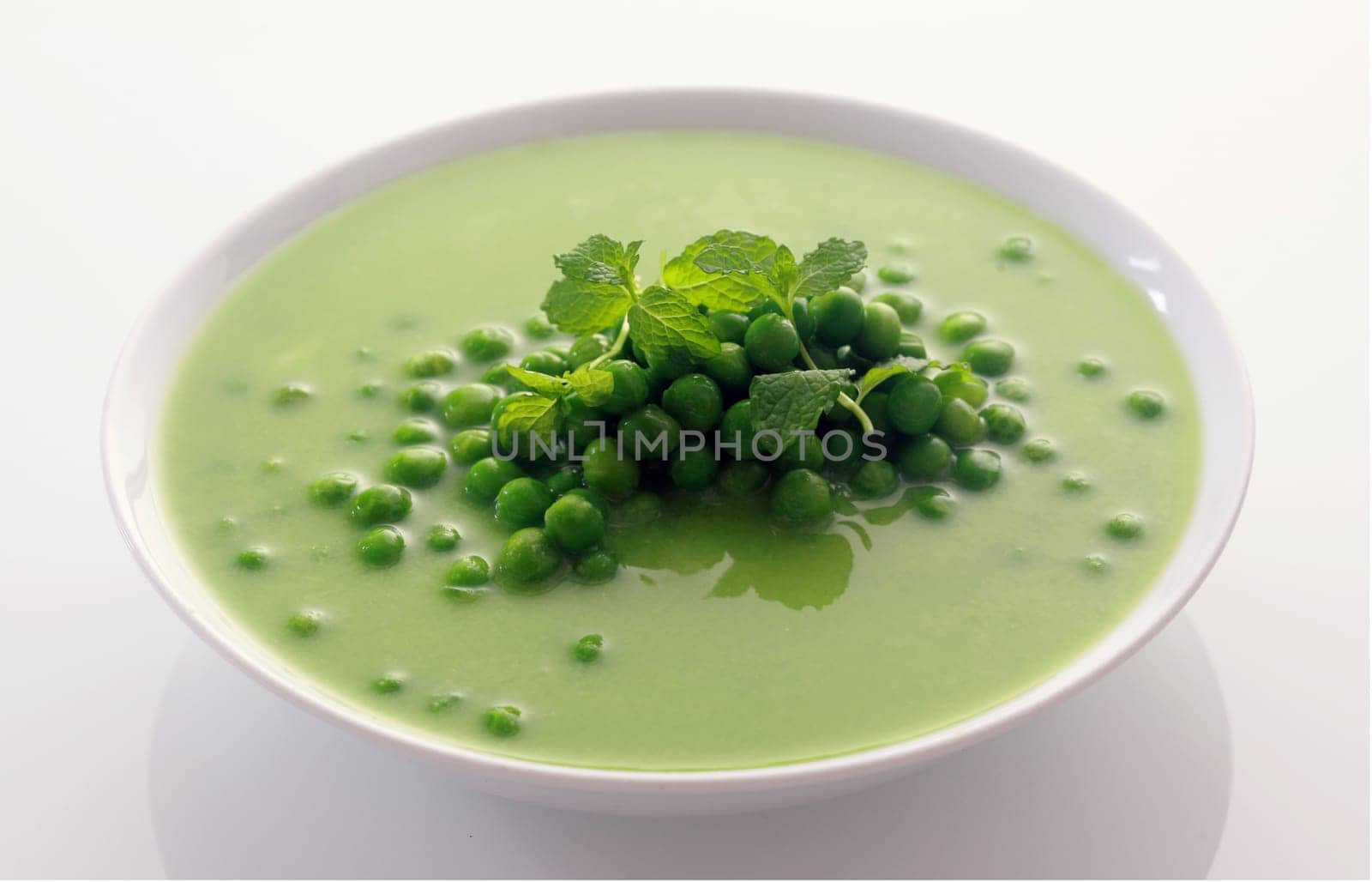 Close up Appetizing Healthy Green Peas Soup on White Bowl Isolated on White Background.