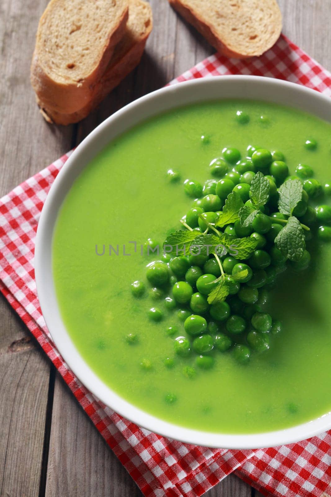 Gourmet Tasty Green Peas Soup Recipe on White Bowl Perfect for Sliced Bread on the Side.