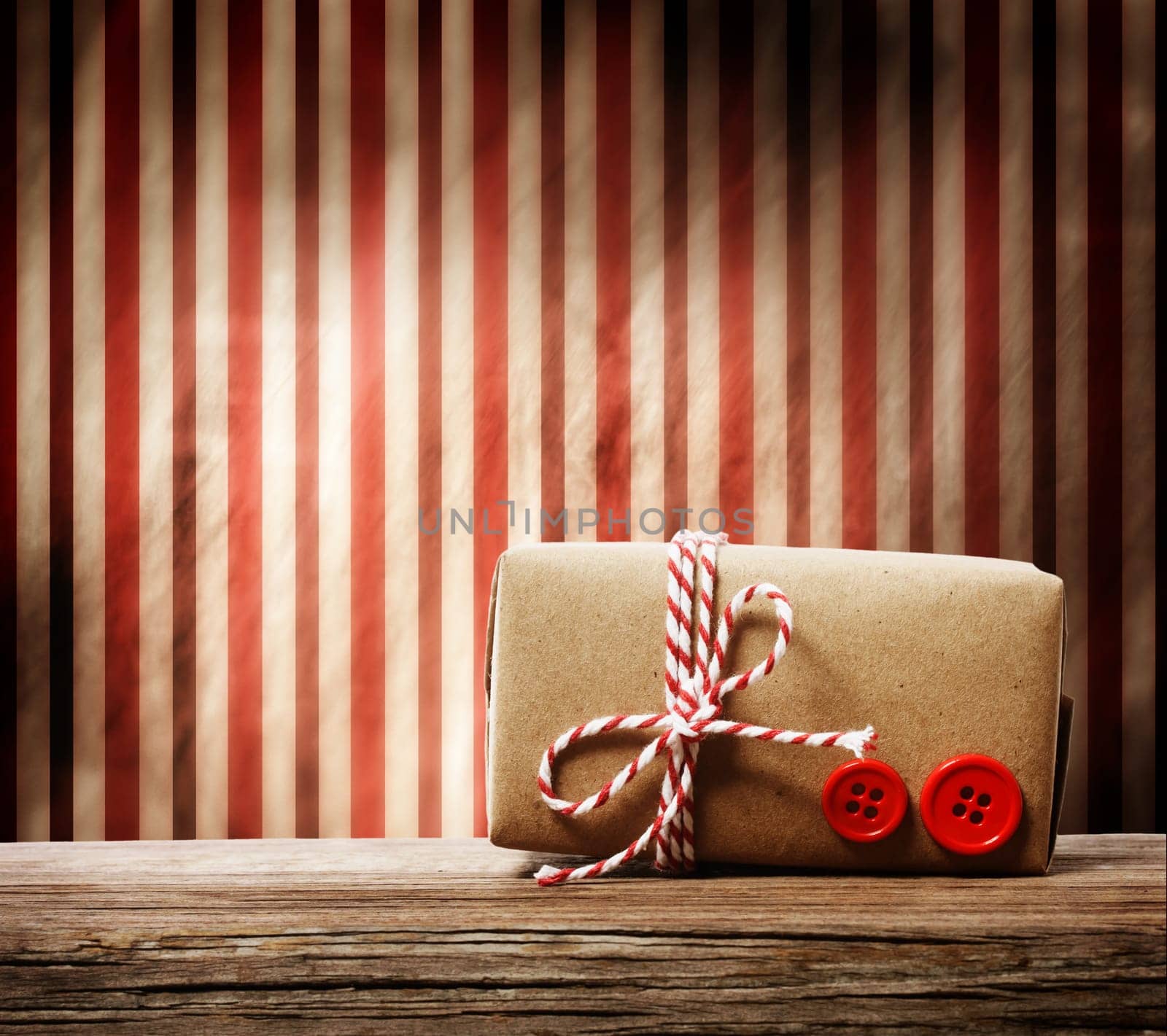 Handmade gift box with red twine cord over striped background