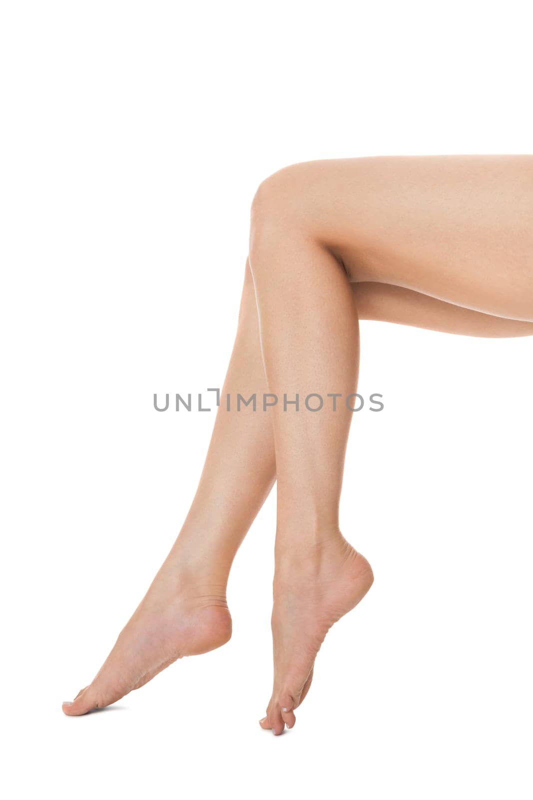 Elegant long shapely naked female legs with bare feet insulated on white with text space