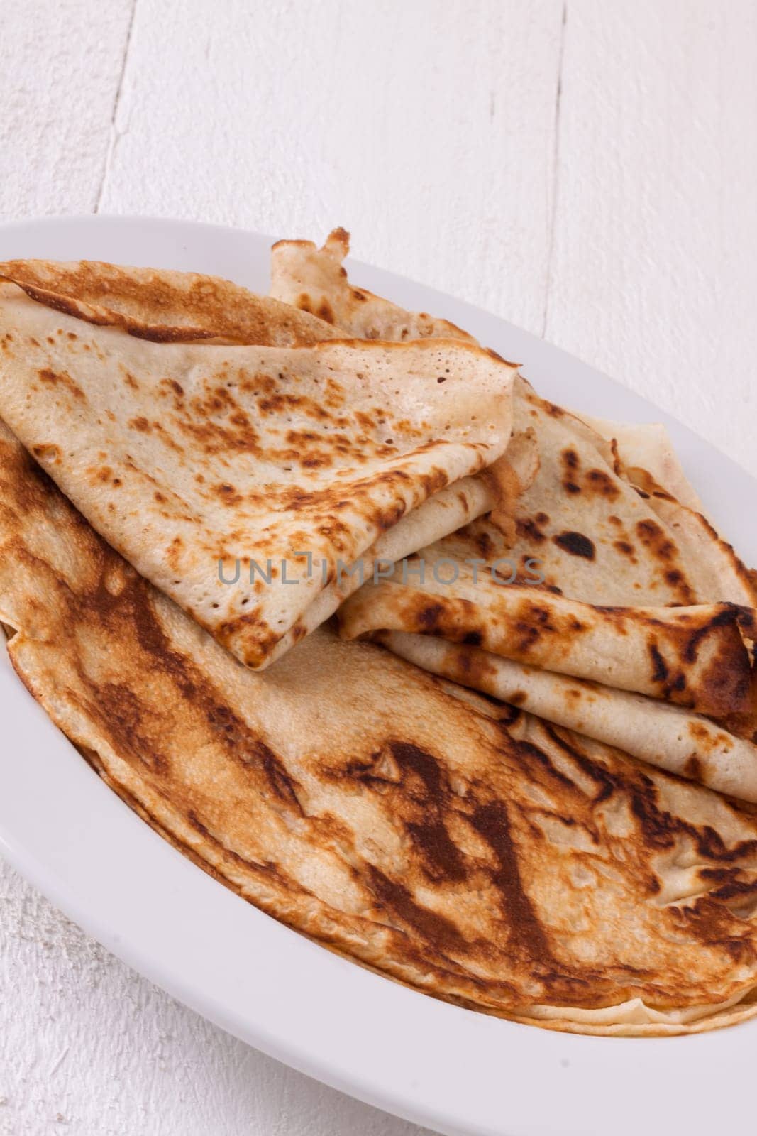 delicious fresh crepes pancakes pancakes on a white plate on a rustic white wooden board