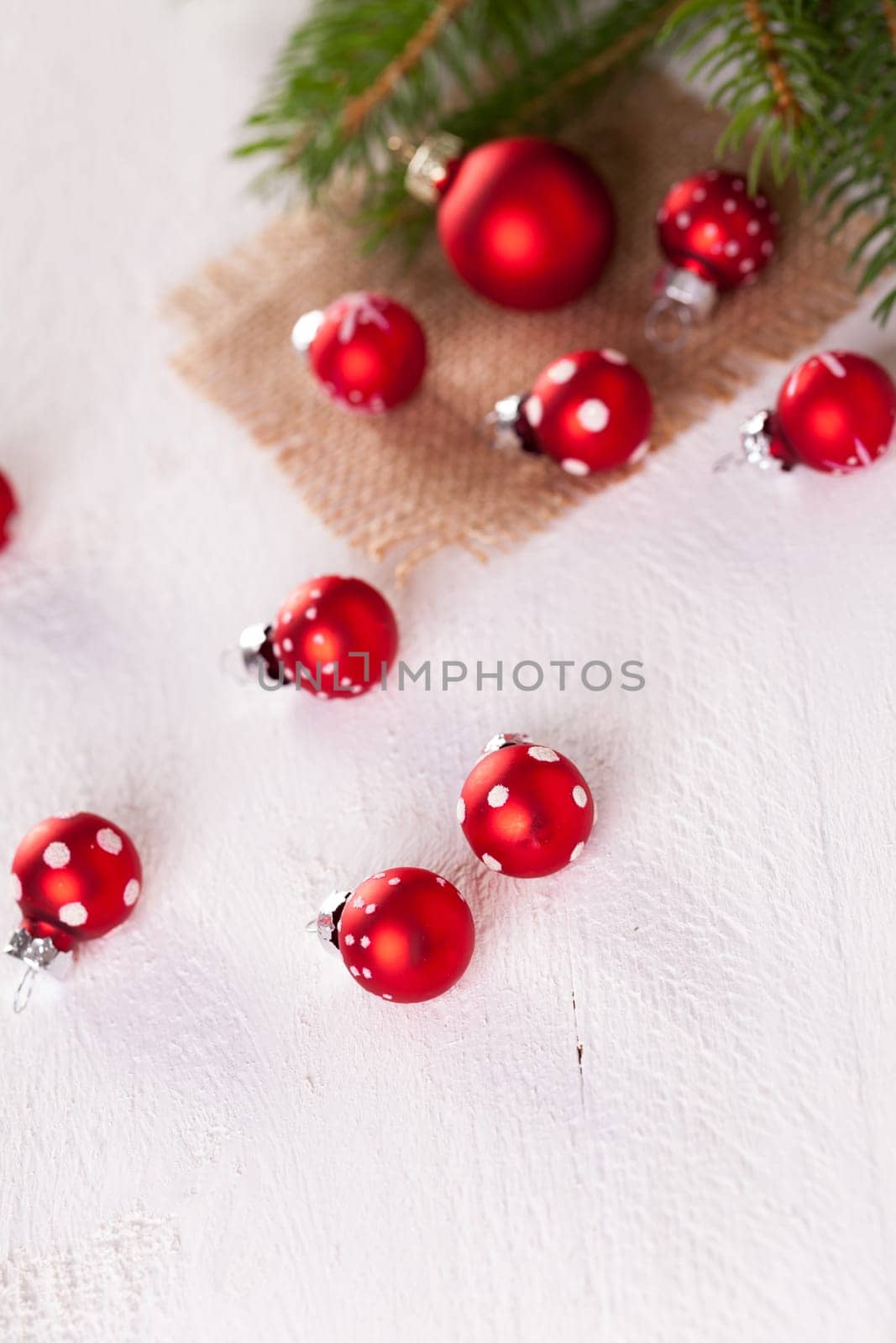 Beautiful red Christmas balls with small white dots with green fir branches on a jute sack