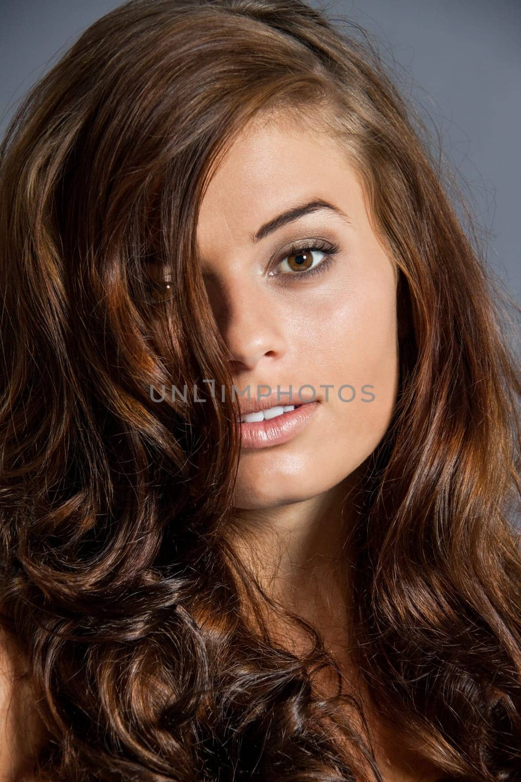 Young attractive brunette woman with curls and white top as portrait