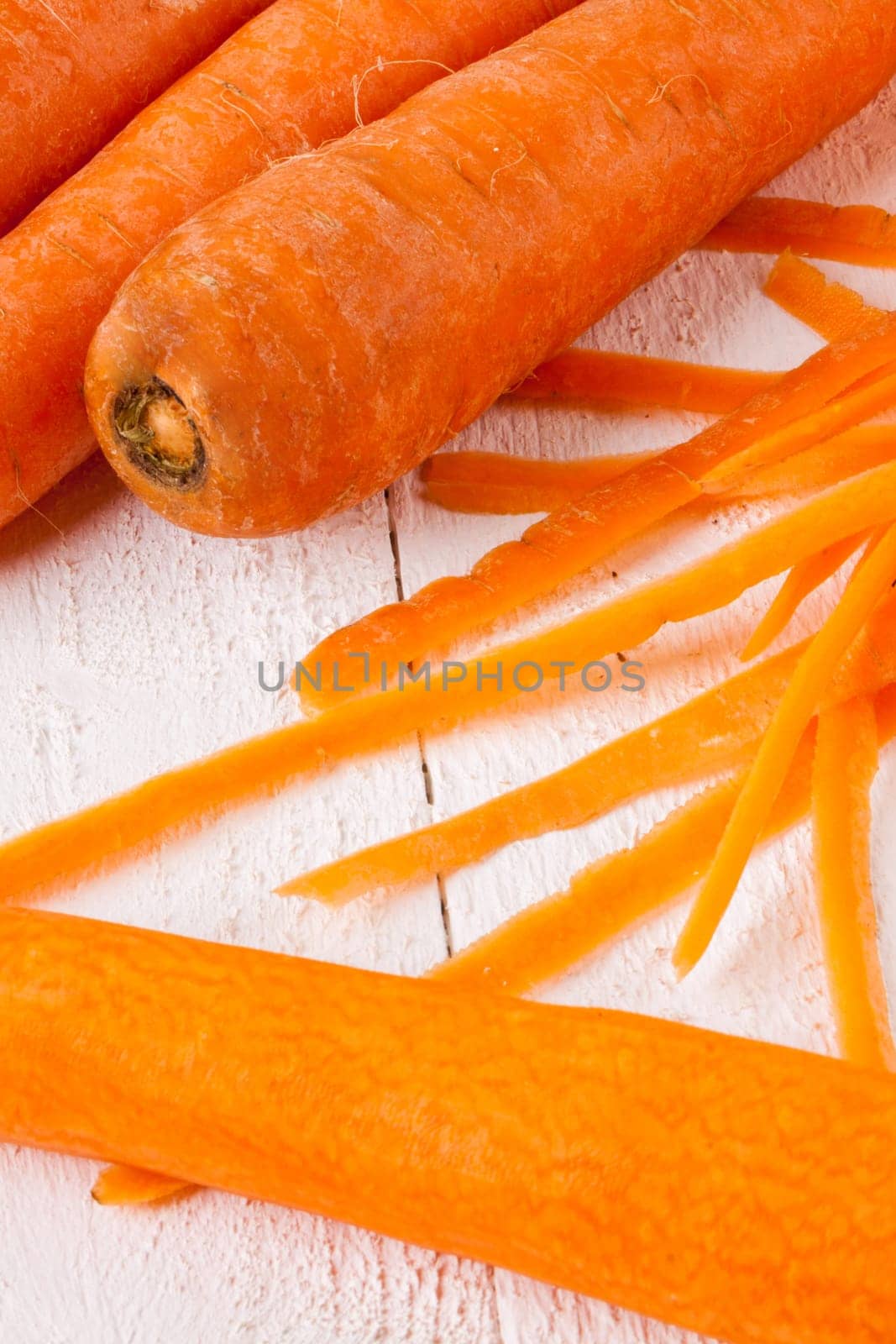 Fresh orange carrots beet turn beets peeled with peelers and bowls on a white wooden board
