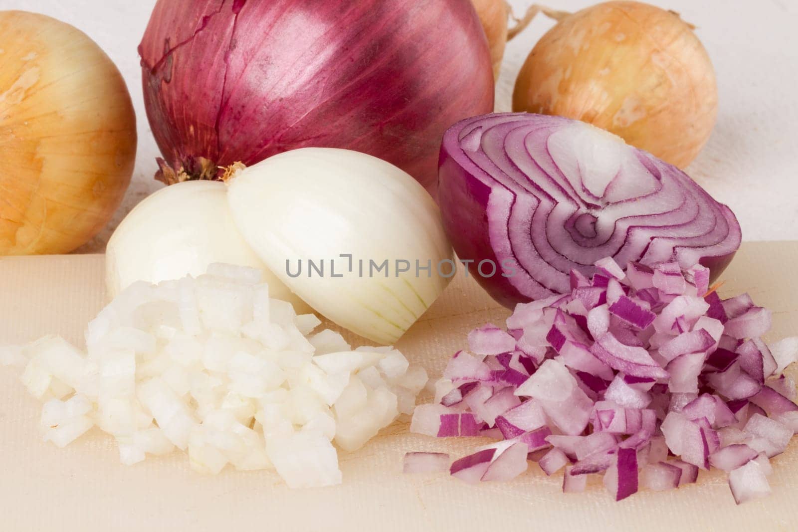 White and red onions peeled and with slurs as a whole and in cubebrunoise as a close-up on cutting board