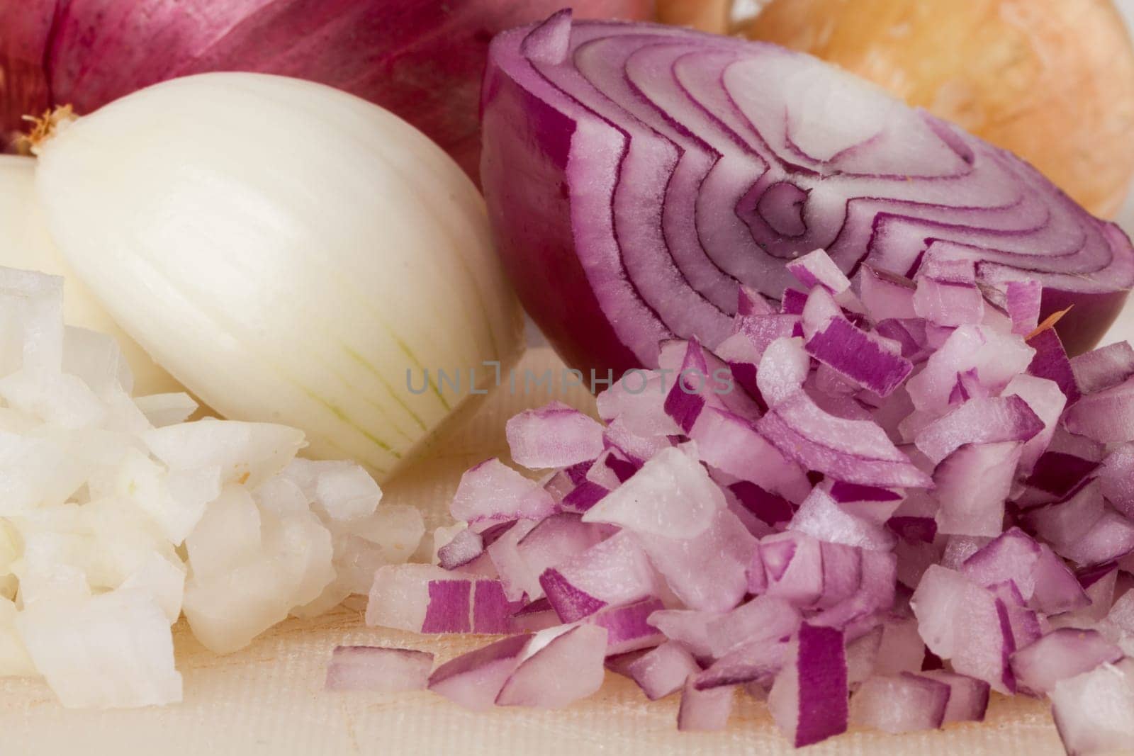 White and red onions peeled and with slurs as a whole and in cubebrunoise as a close-up on cutting board