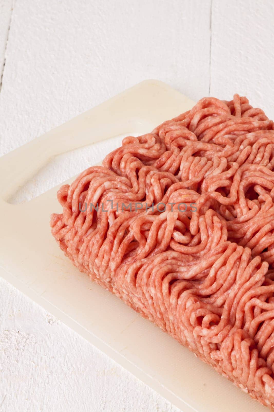 Minced meat raw beef and pork mixed as a block of protective atmosphere as a close-up on a white plate