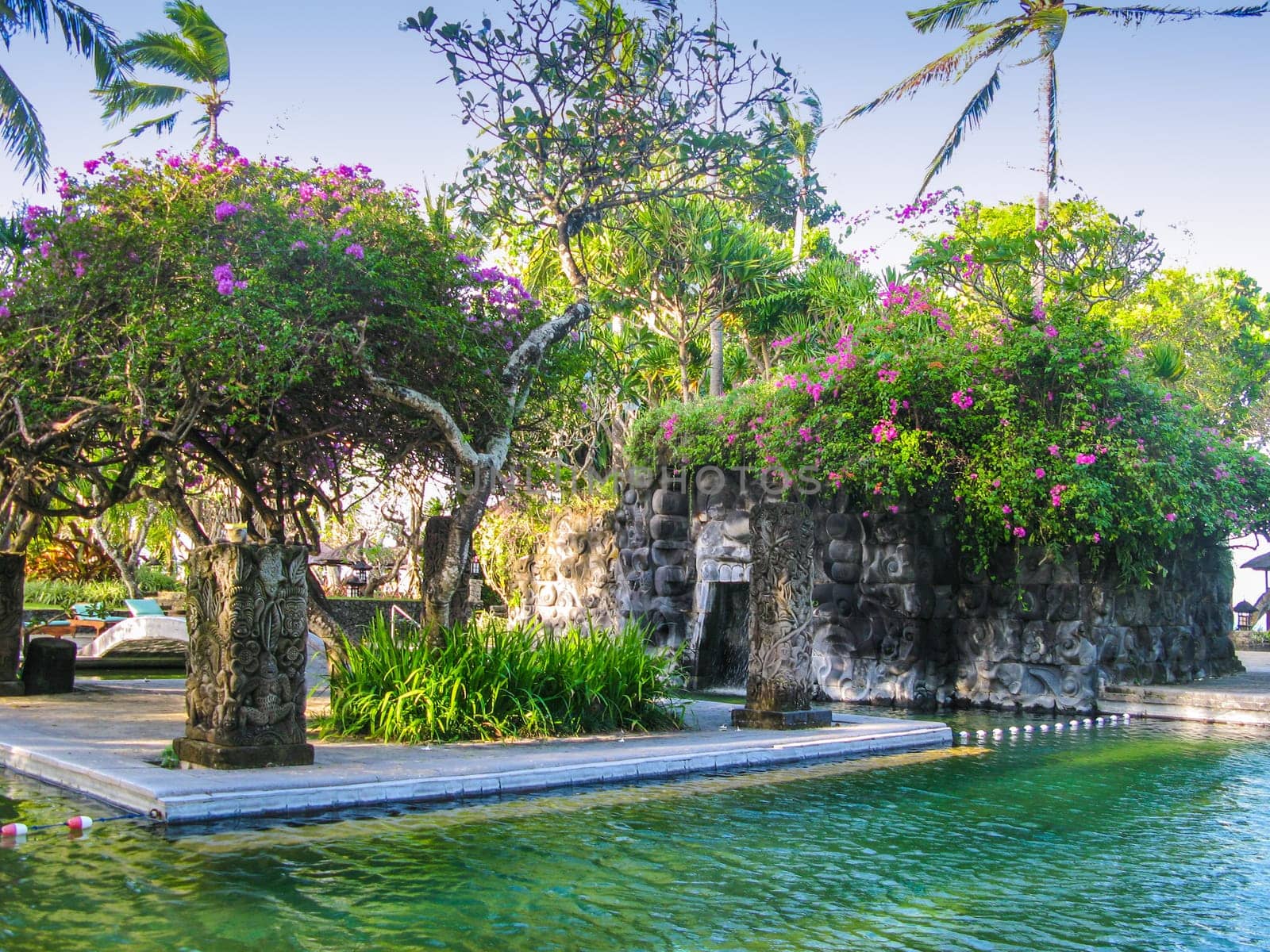 Pool in Bali with a small ornate cave made of stone.