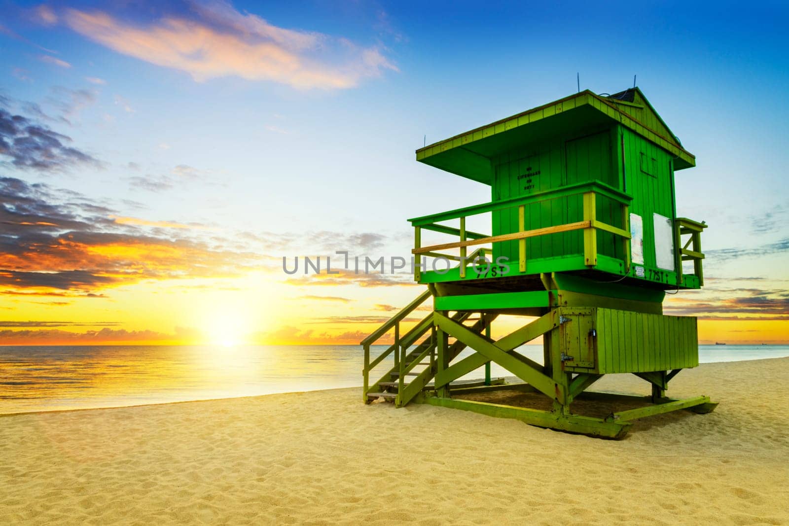 Miami South Beach sunrise with lifeguard tower and coastline with colorful cloud and blue sky.
