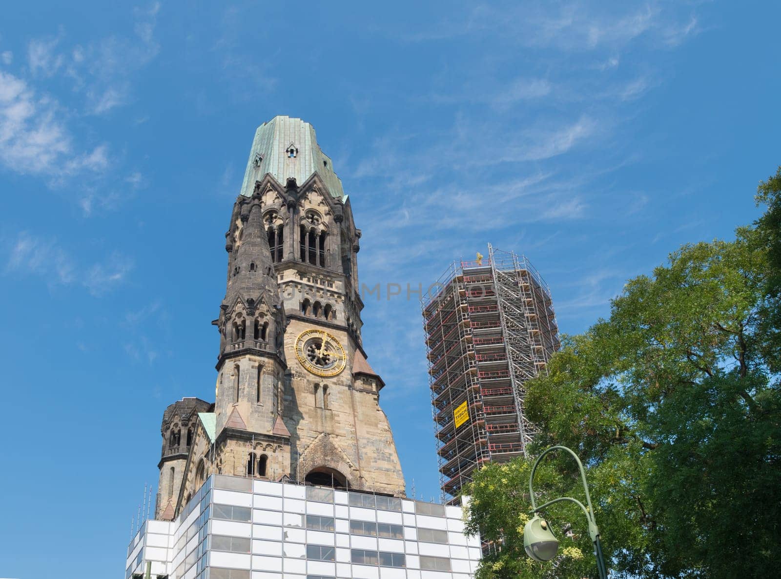 Kaiser Wilhelm Memorial Church next to a modern bell tower in Berlin, Germany. Historical church hit and damaged by allied air forces during the Second World War and never restored.