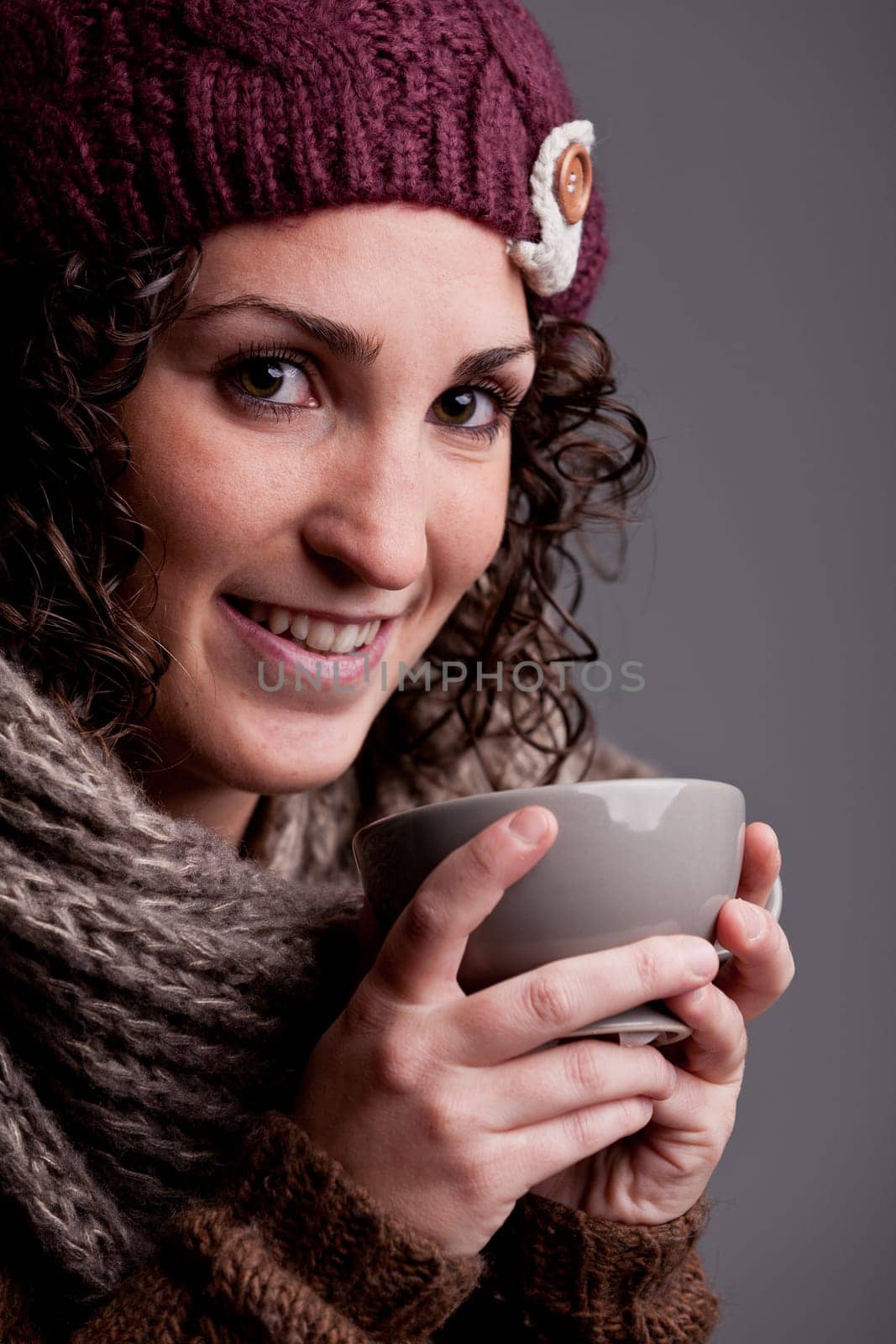 it's winter and this girl with wool hat and scarf drinks a hot chocolate or hot tea or milk from a big mug and she's happy