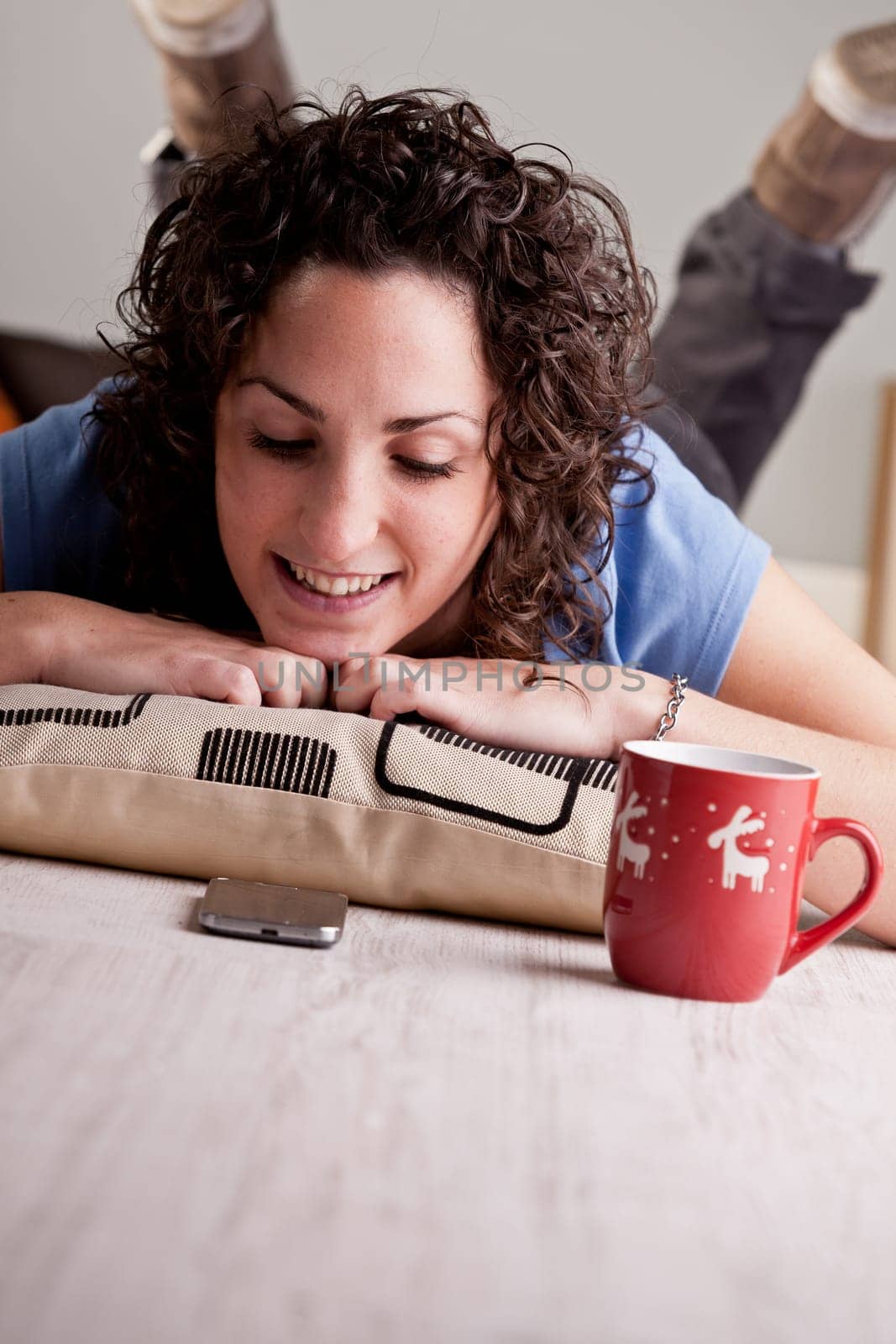 this girl reads text messages in her mobile phone while drinking a chocolate from her Christmas mug